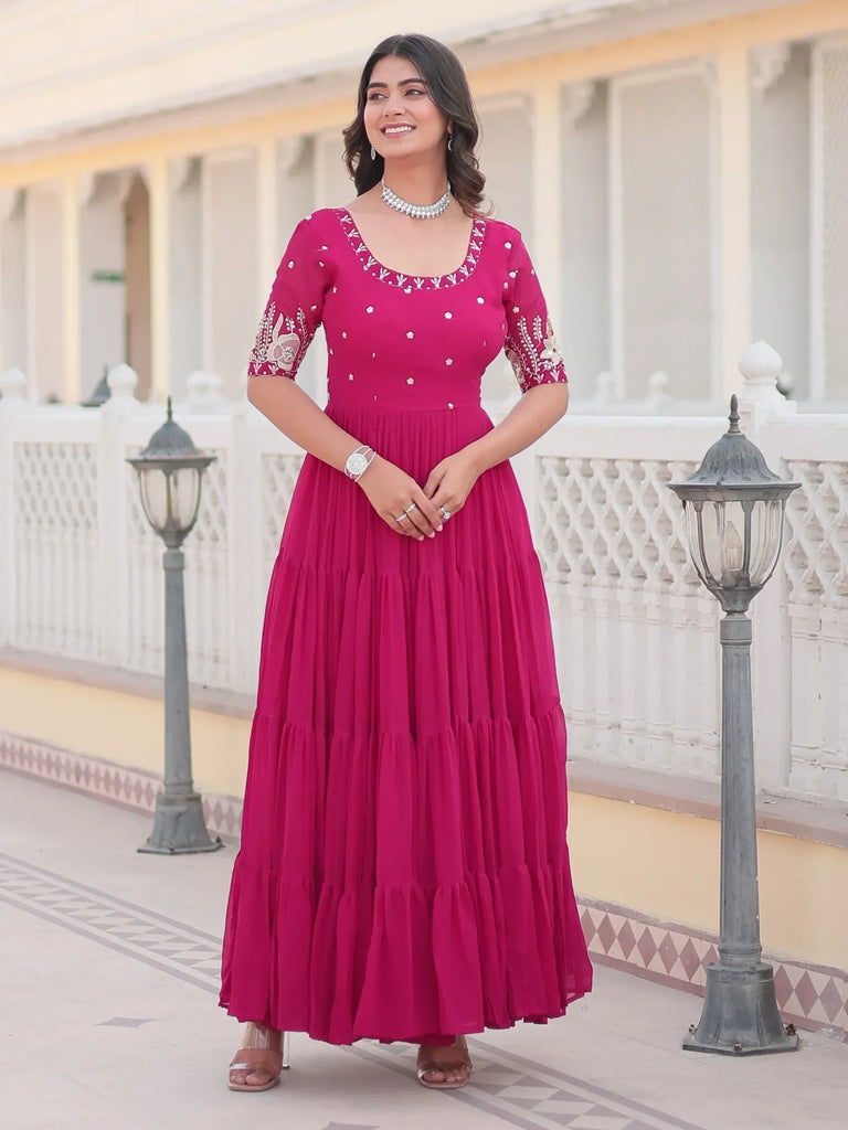 Woman in pink embroidered ethnic gown with tiered skirt, perfect for Indian occasions