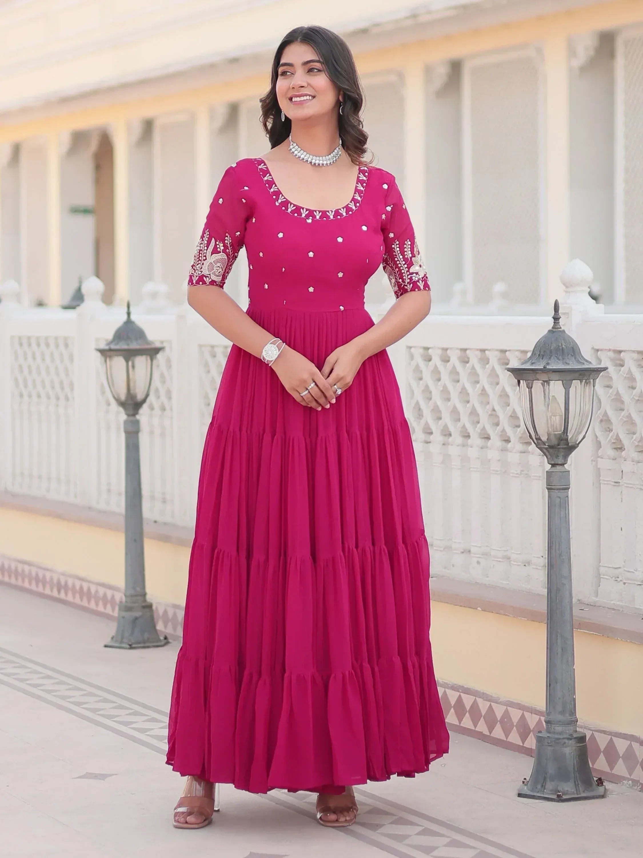 Woman in pink embroidered ethnic gown with tiered skirt, perfect for Indian occasions