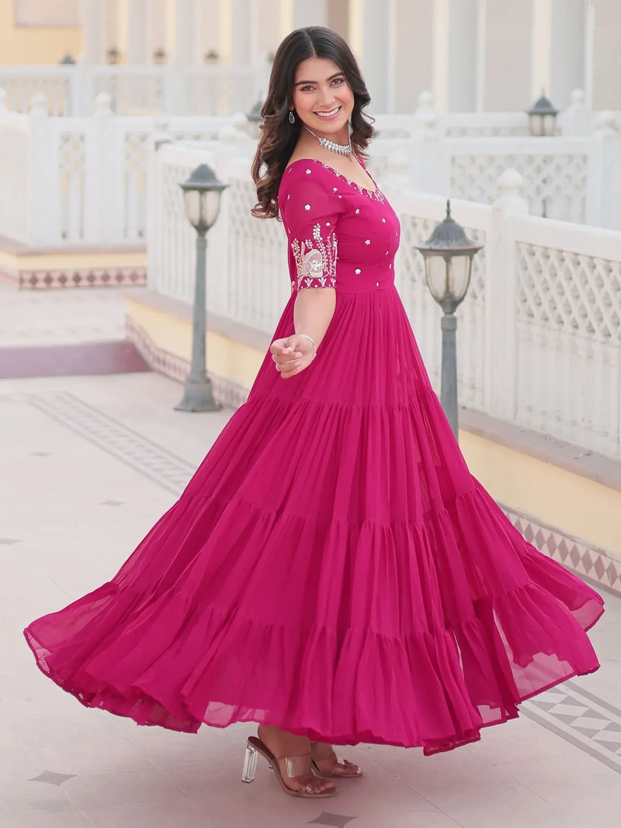 Fuchsia ethnic gown with embroidered sleeves and tiered skirt, perfect for Indian celebrations