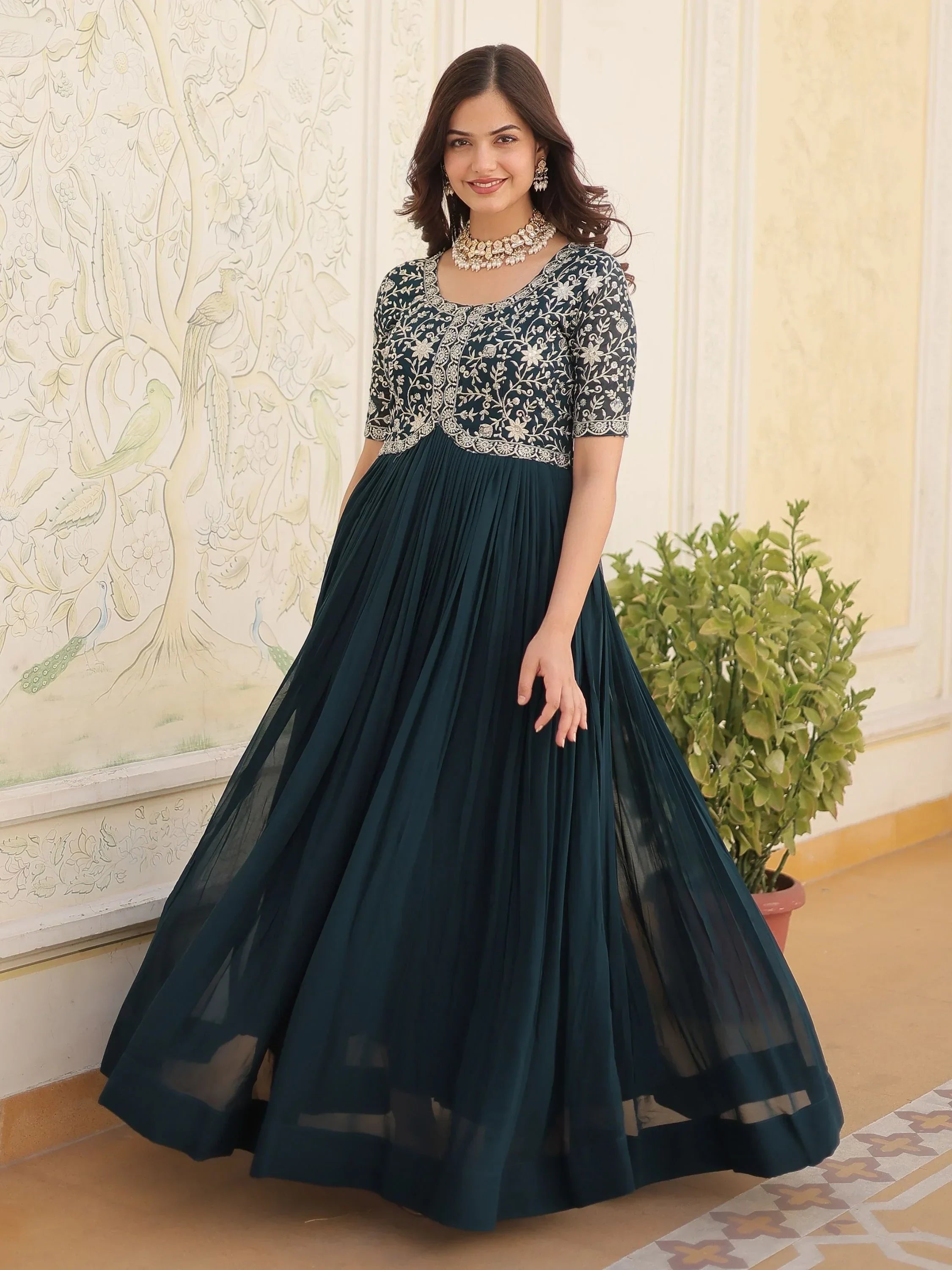 Woman in navy blue embroidered ethnic gown with sheer skirt, traditional jewelry, indoor backdrop