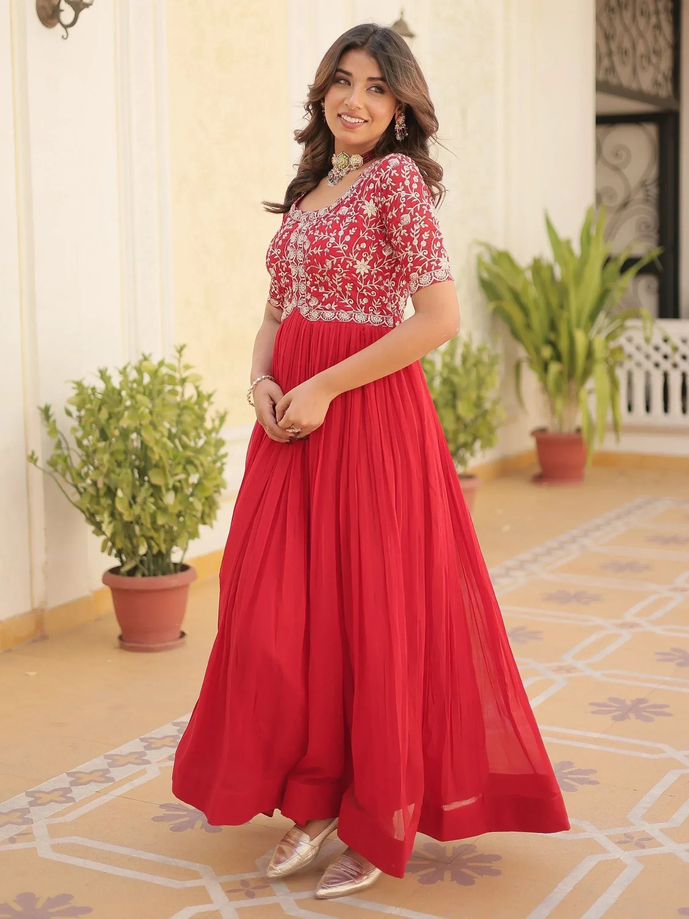 Red ethnic gown with white embroidery, pleated skirt, and gold jewelry for Indian occasions