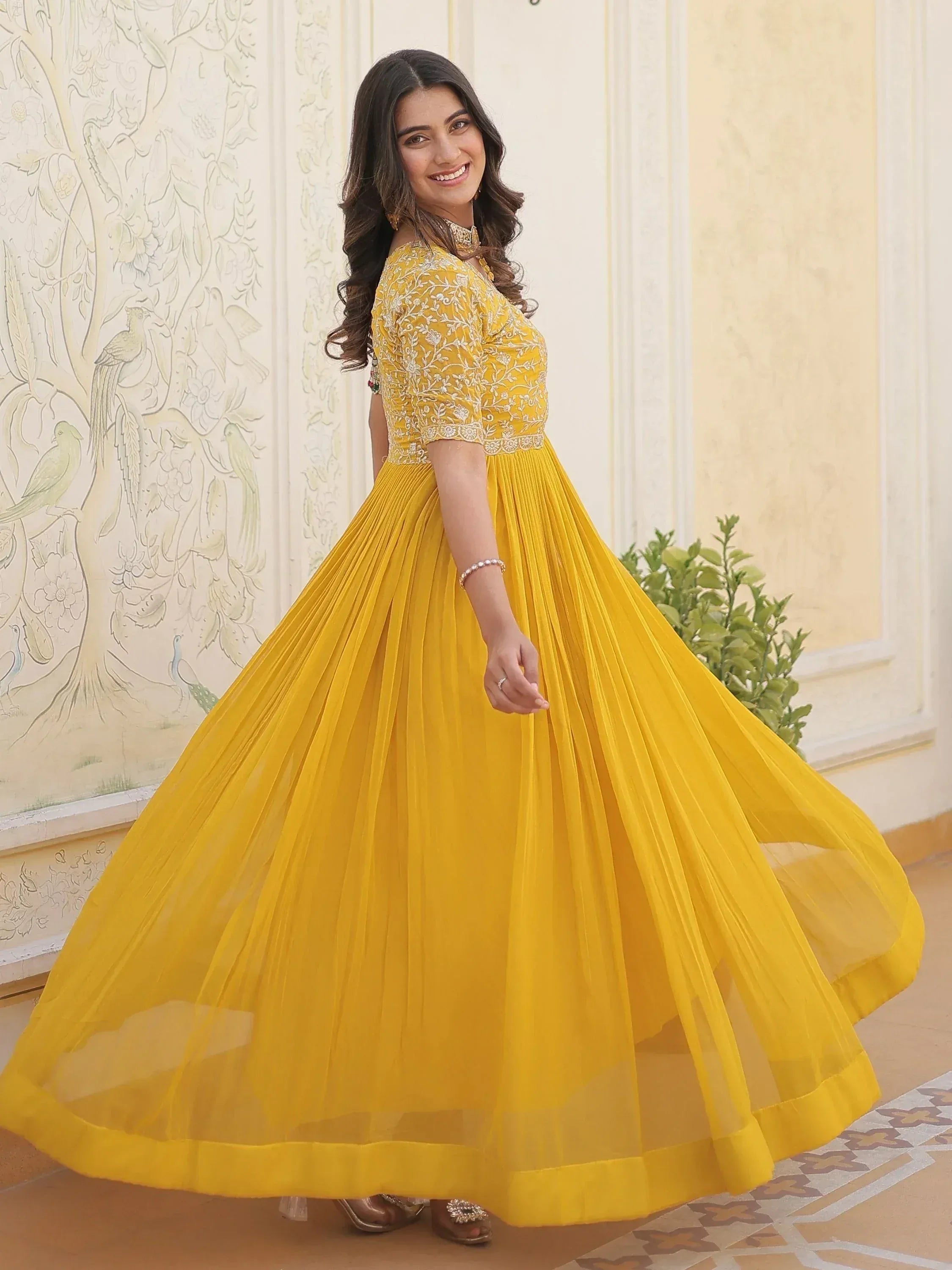 Yellow embroidered ethnic gown with pleated skirt, perfect for Indian weddings and festive occasions.