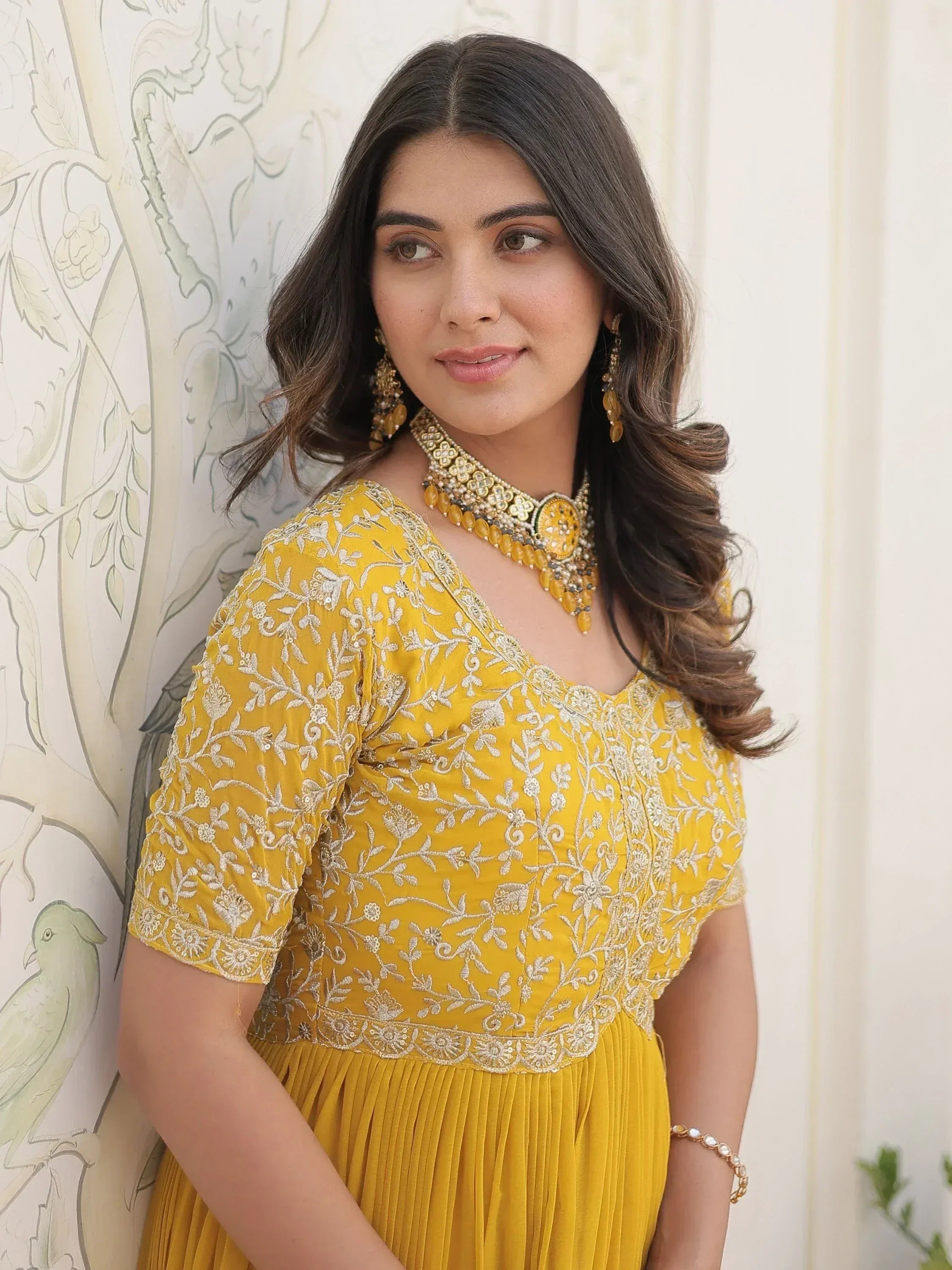 Yellow embroidered ethnic gown with floral detailing and matching jewelry for Indian wear
