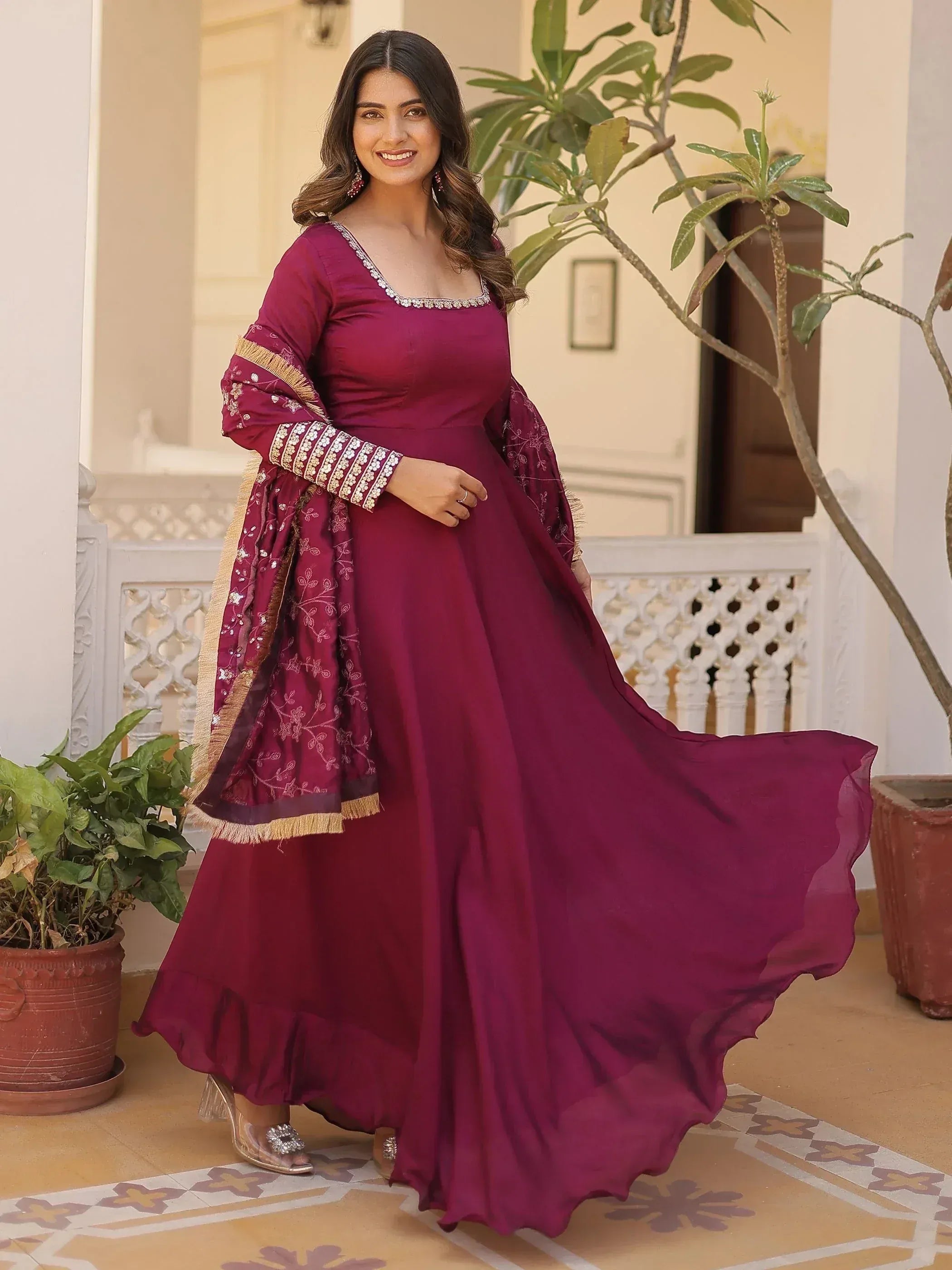 Woman in maroon ethnic gown with embroidery, perfect for Indian occasions and festive wear.