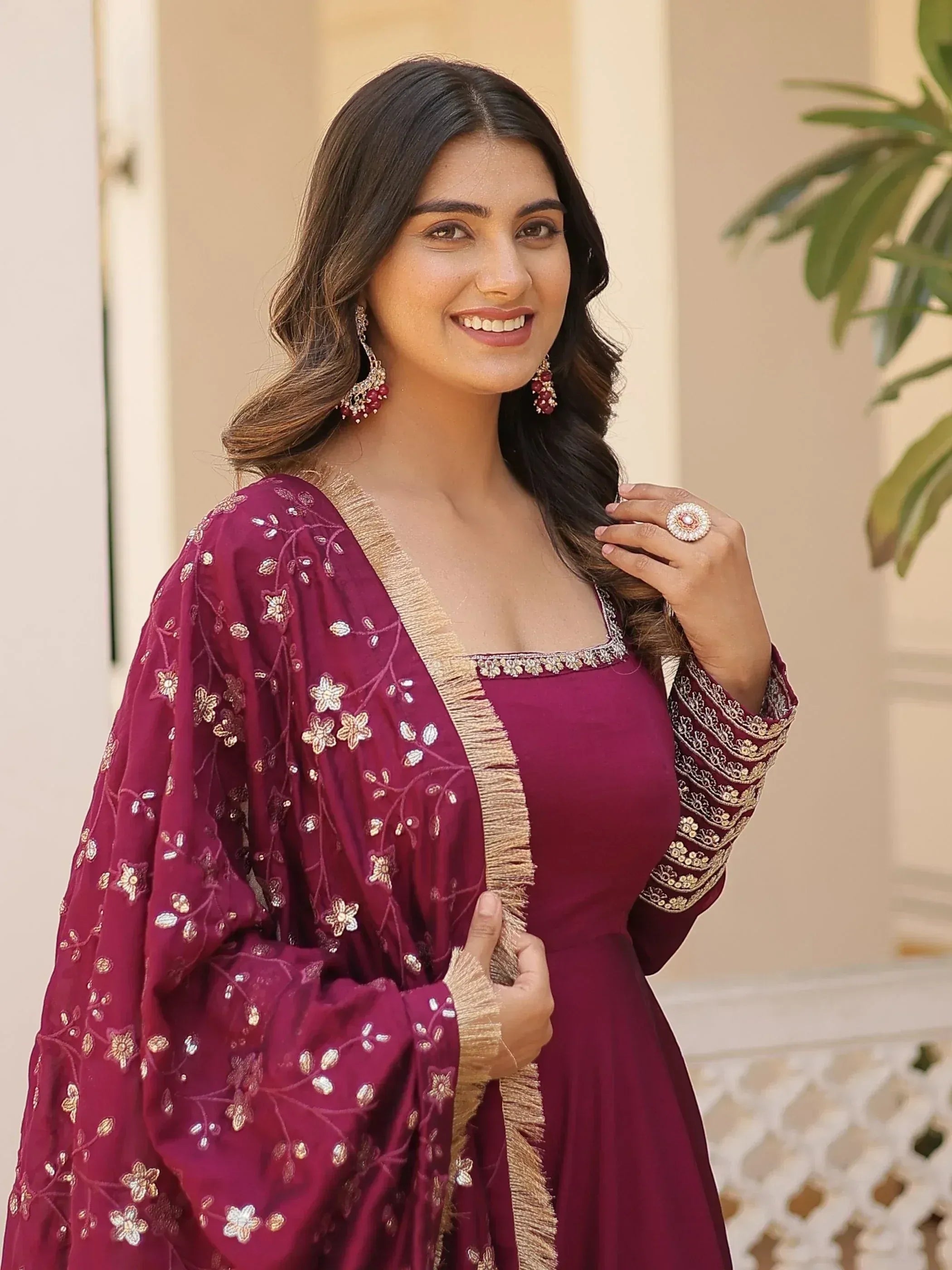 Woman in maroon embroidered ethnic gown with gold detailing, perfect for Indian festive occasions