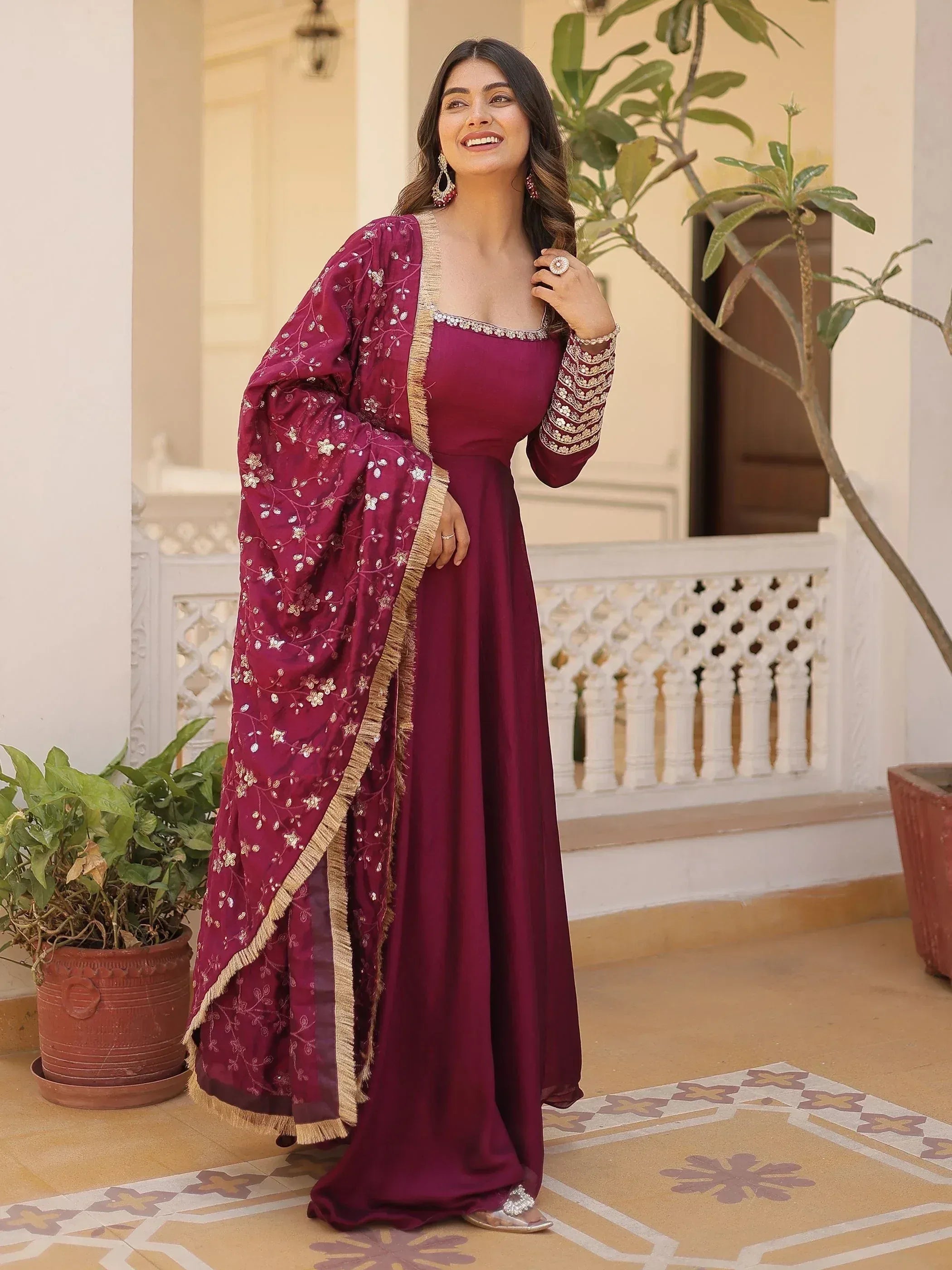 Woman in maroon ethnic gown with floral embroidery and gold trim, perfect for Indian occasions