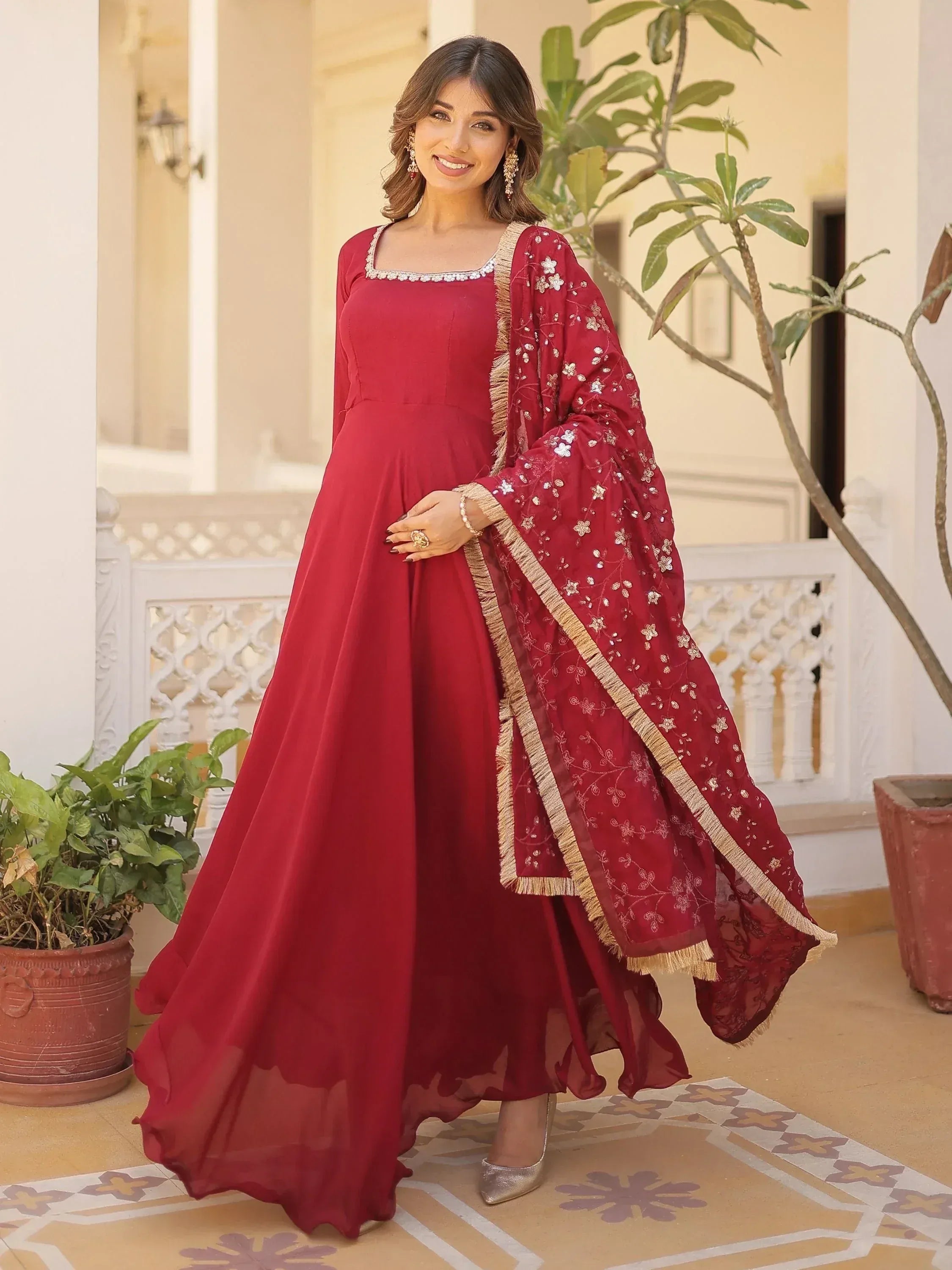 Maroon ethnic gown with floral embroidery and gold trim, perfect for Indian festive occasions
