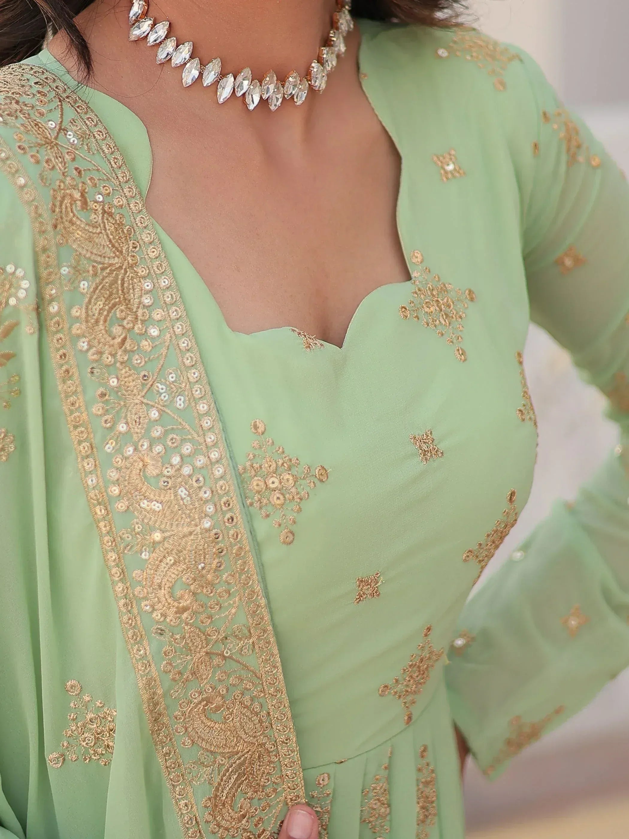Mint green ethnic gown with gold embroidery and sequin detailing, paired with crystal necklace