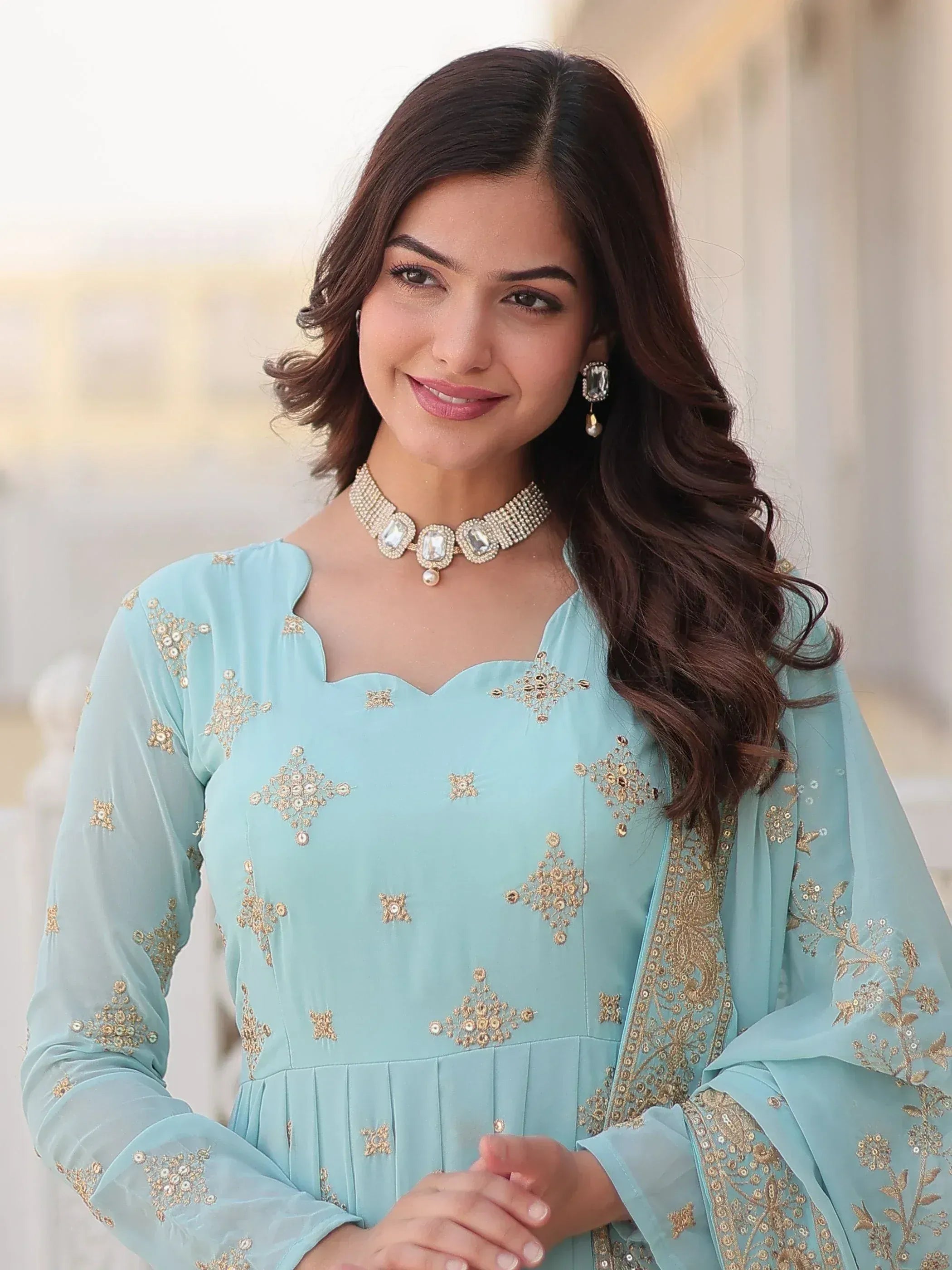 Woman in light blue embroidered ethnic gown with gold detailing and statement jewelry