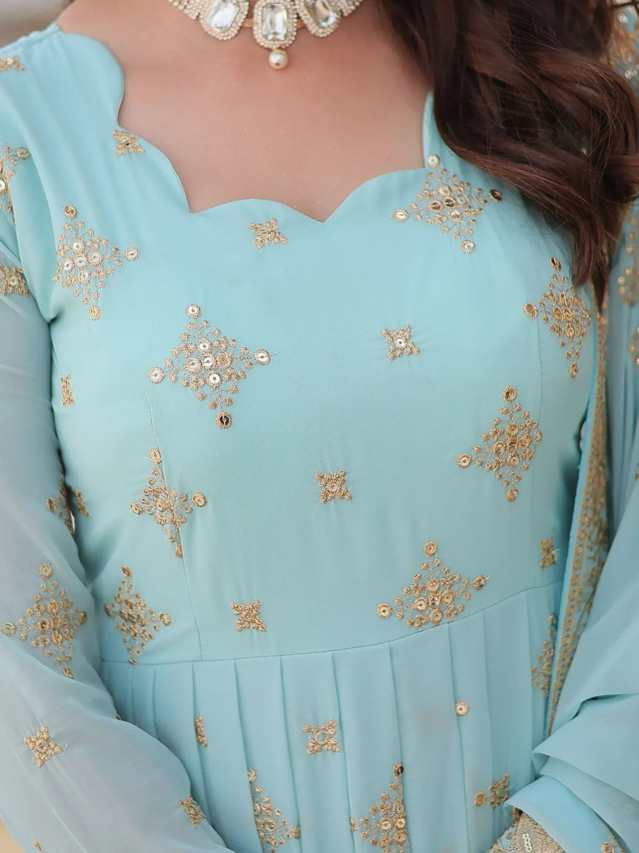 Light blue ethnic gown with gold embroidery and scalloped neckline, paired with statement jewelry