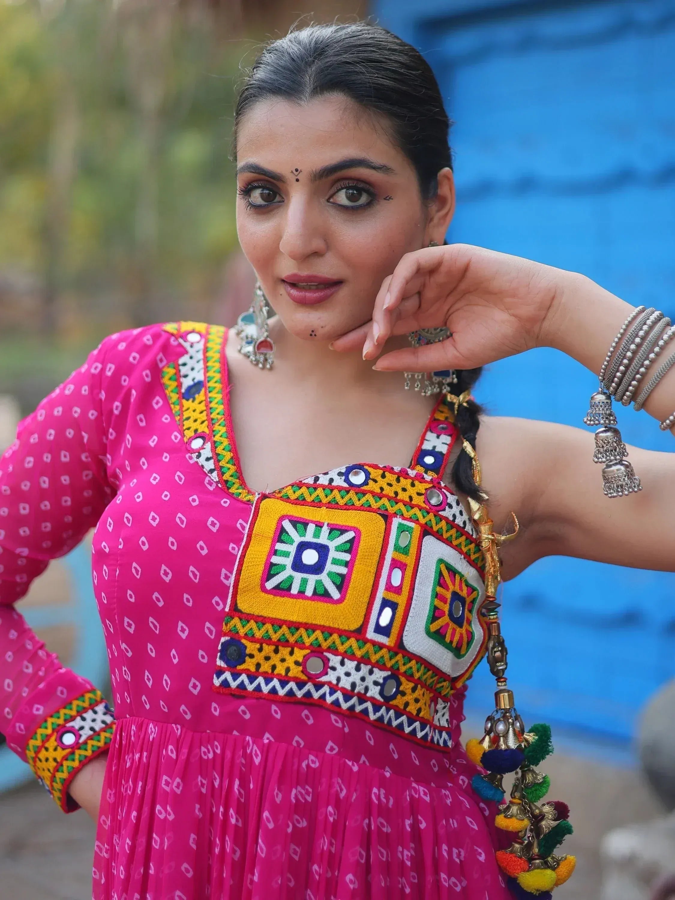 Woman in vibrant pink ethnic gown with mirror work, jhumka earrings, and traditional Indian jewelry