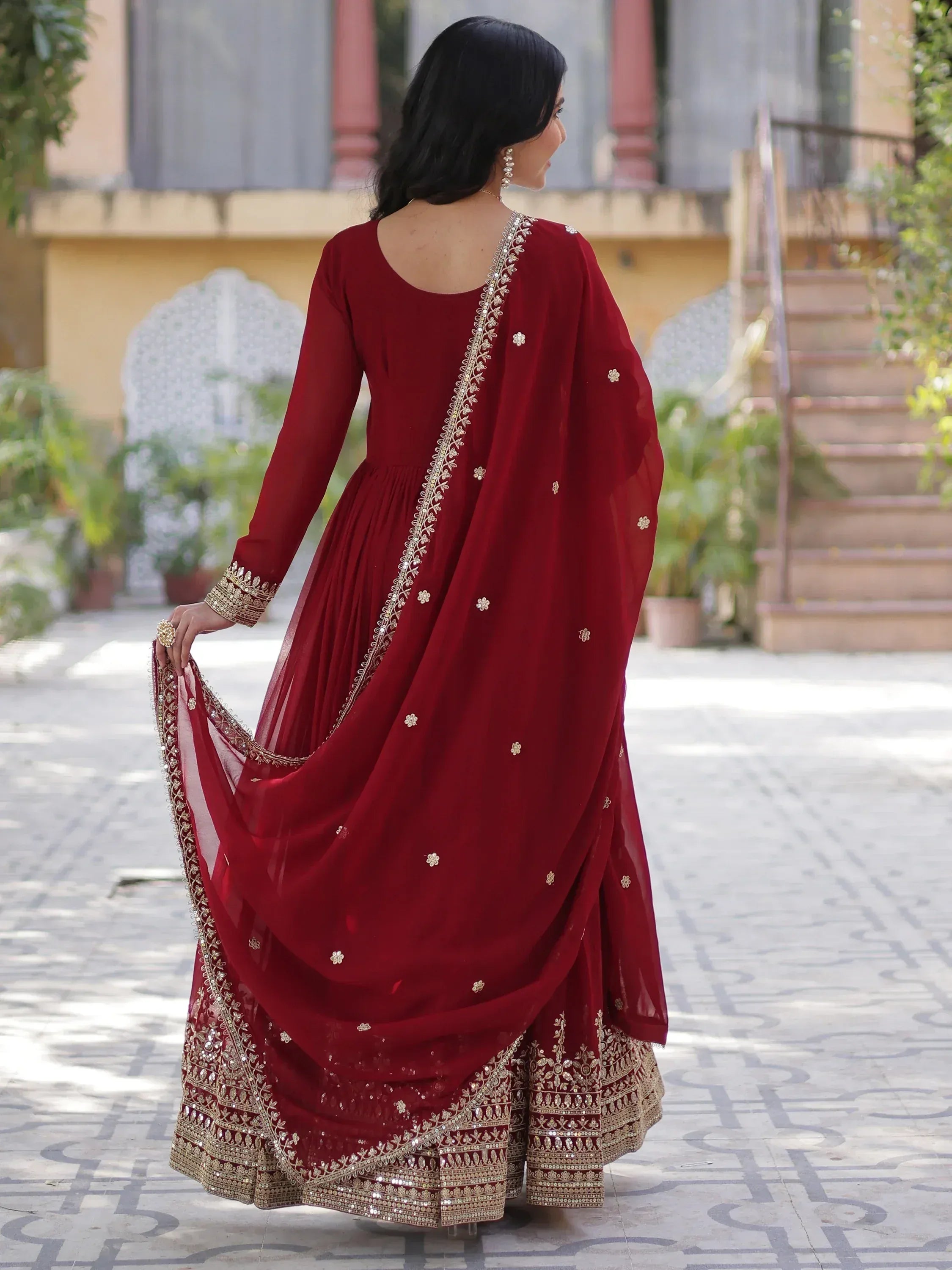 Elegant maroon ethnic gown with gold embroidery, perfect for Indian weddings or festive occasions.