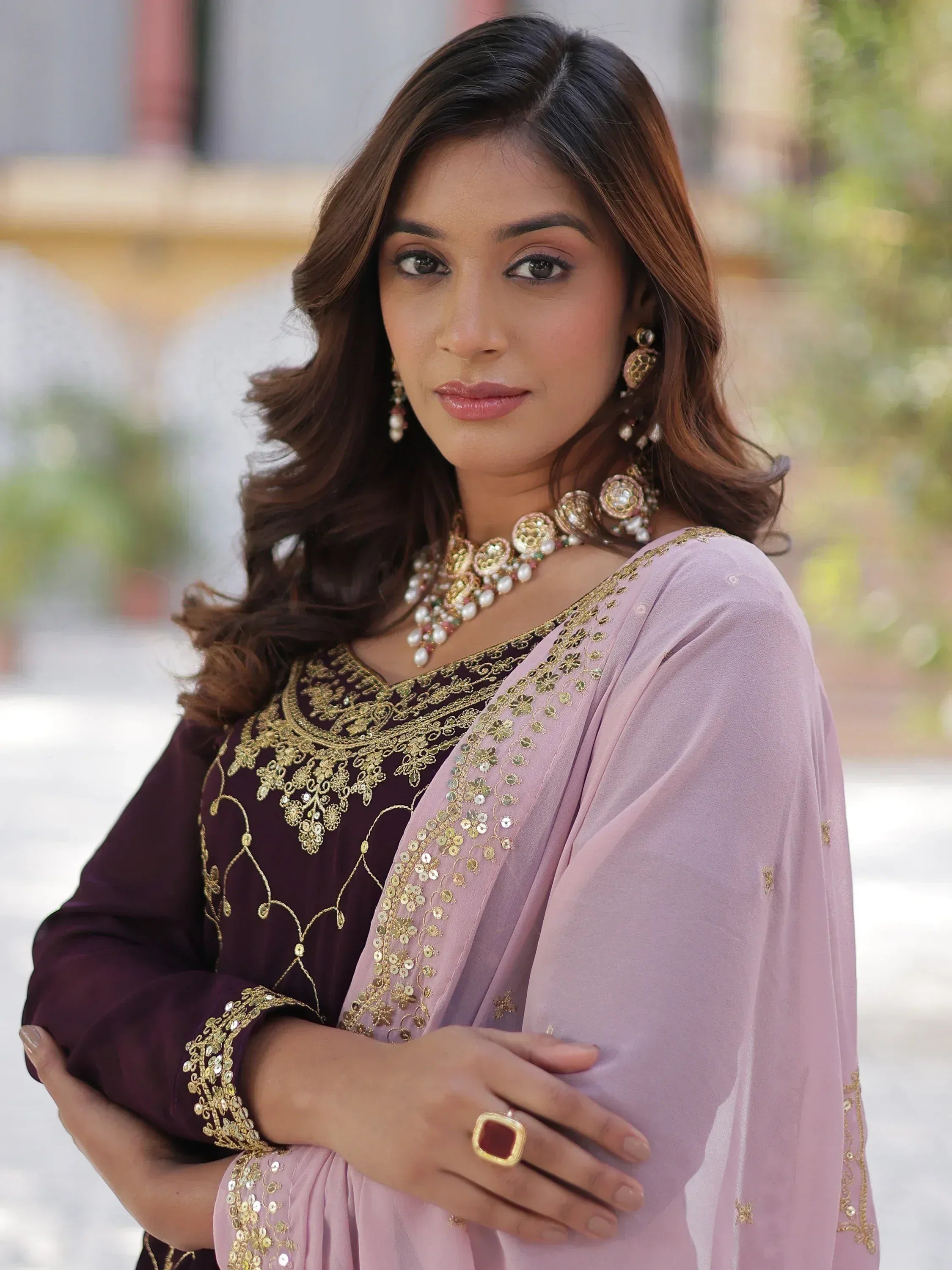 Elegant woman in maroon and pink ethnic wear with gold embroidery and traditional jewelry