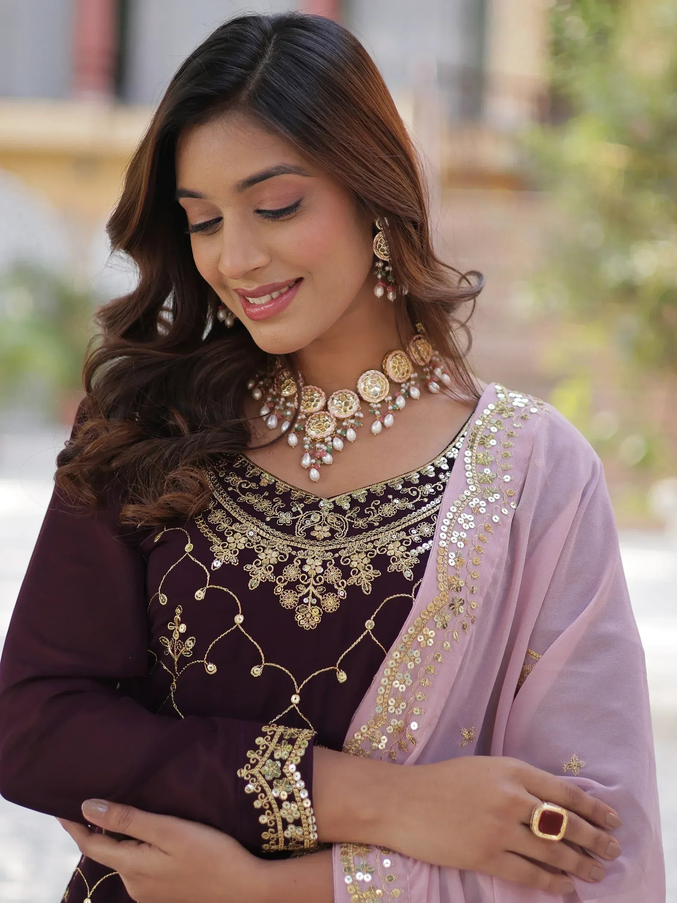 Woman in maroon embroidered salwar kameez with pink dupatta, gold jewelry, perfect for Indian ethnic wear