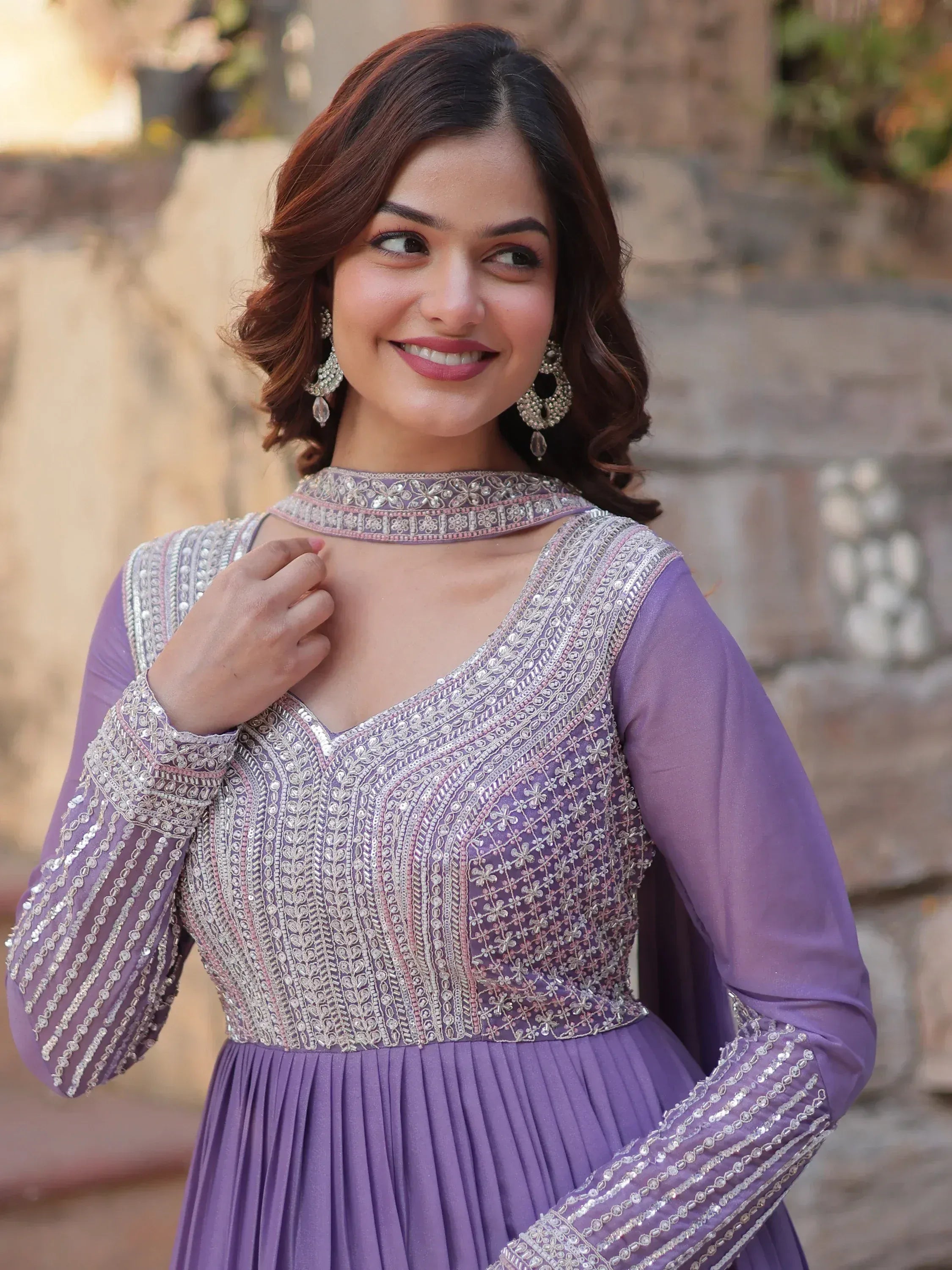 Woman in purple embroidered ethnic gown with choker neckline and statement earrings, perfect for Indian occasions.
