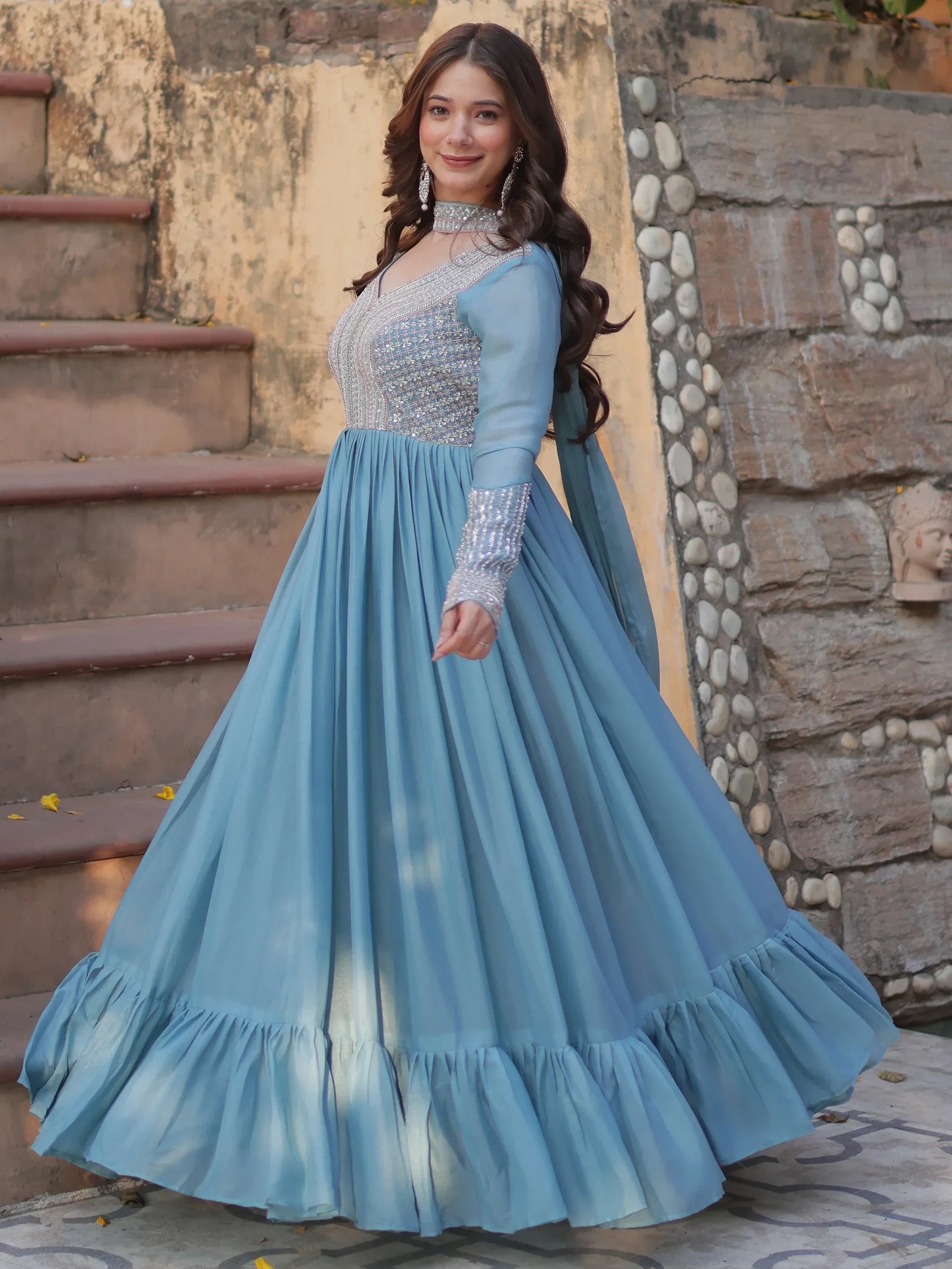 Woman in light blue embroidered Anarkali gown with sheer sleeves, posing outdoors