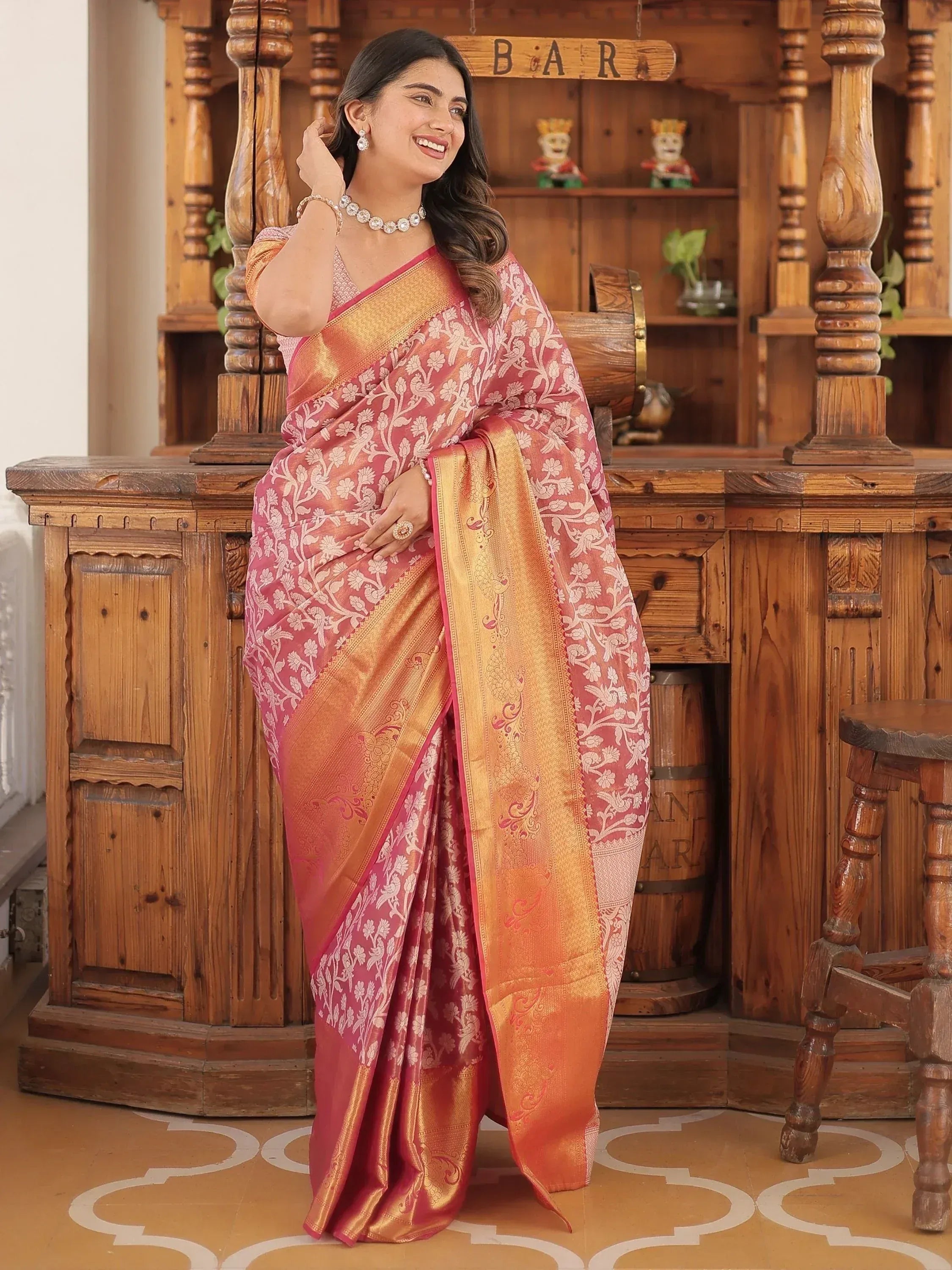 Woman in pink and gold floral saree with zari border, traditional Indian ethnic wear