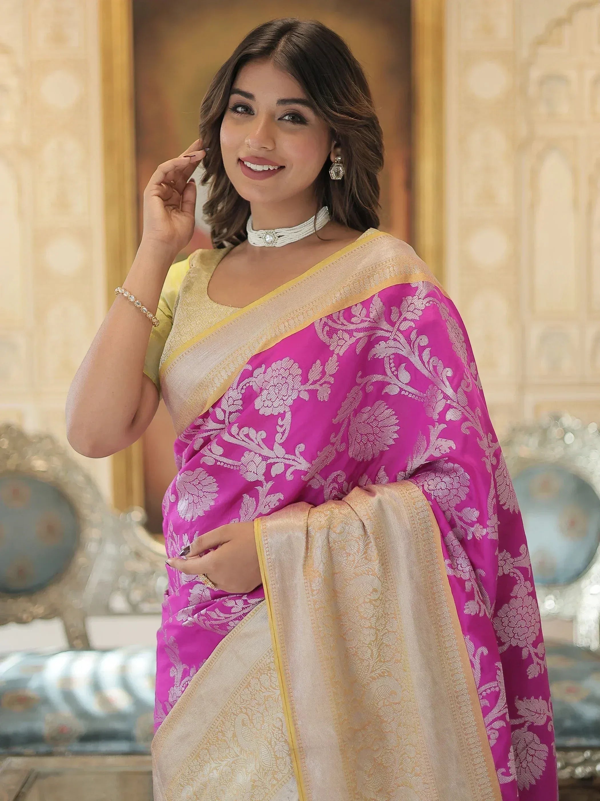 Woman in vibrant pink floral saree with gold border, styled for ethnic occasions