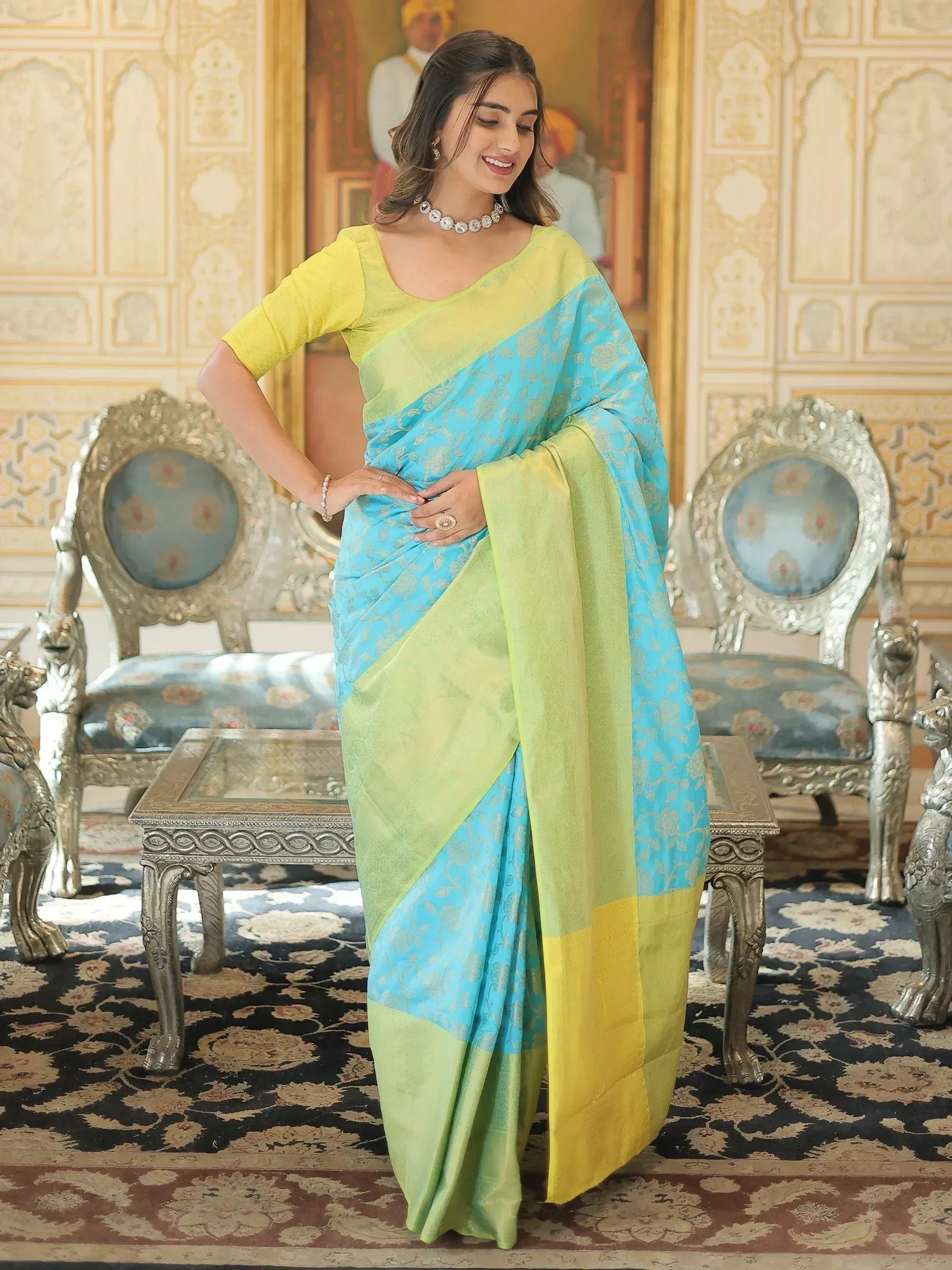 Woman in vibrant blue and green designer saree with gold motifs, paired with yellow blouse, elegant ethnic wear