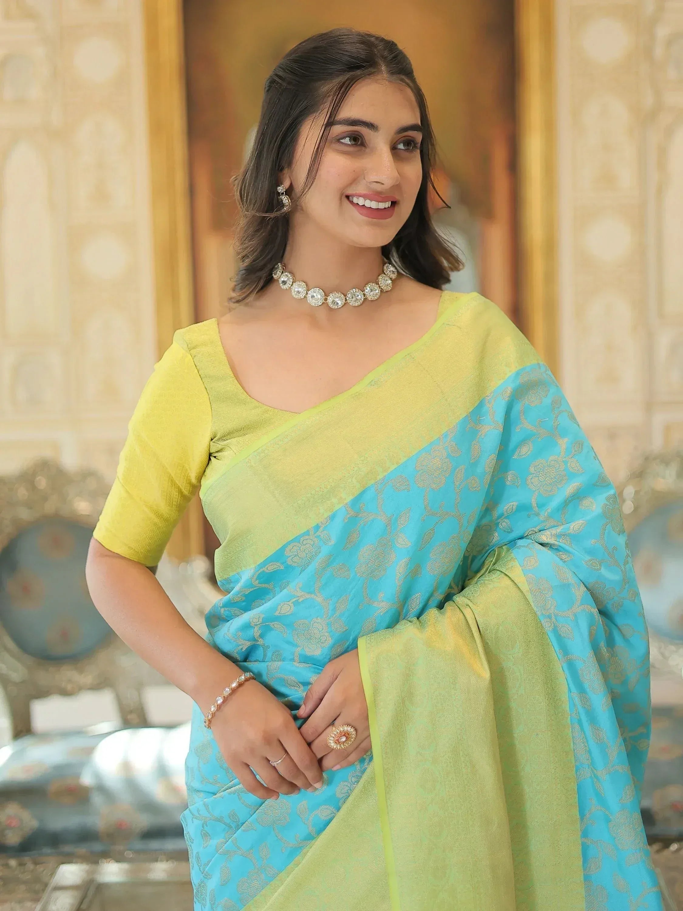 Woman in vibrant green and blue designer saree with gold floral patterns, perfect for ethnic occasions