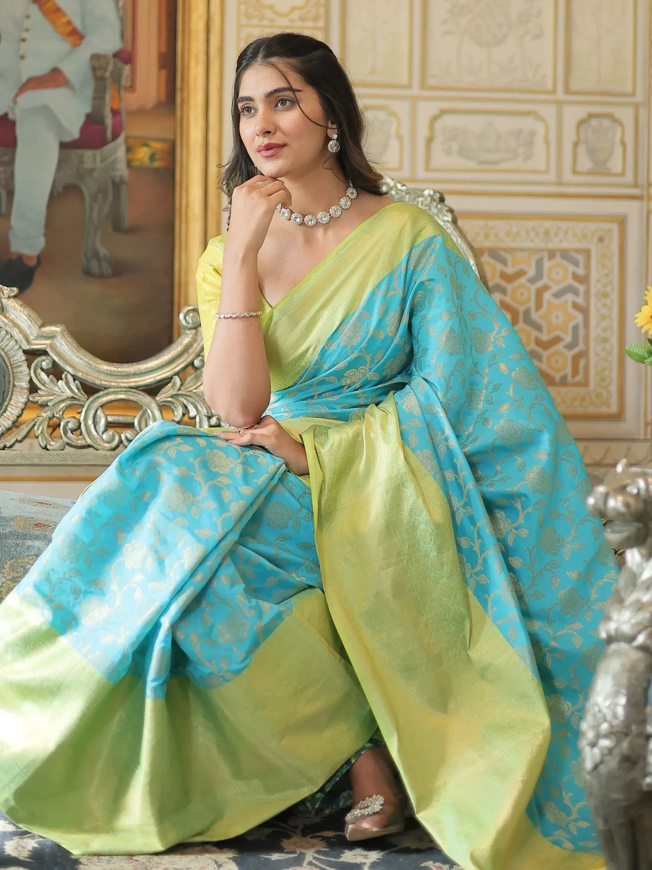 Woman in elegant green and blue designer saree with gold floral patterns, styled for Indian ethnic wear