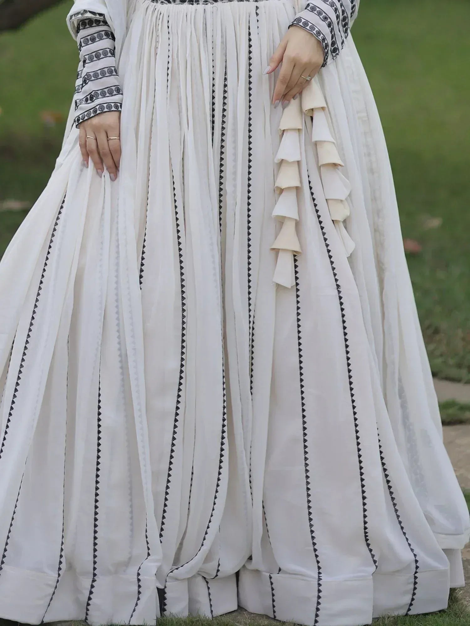 White ethnic gown with black embroidery and ruffle details, perfect for Indian occasions