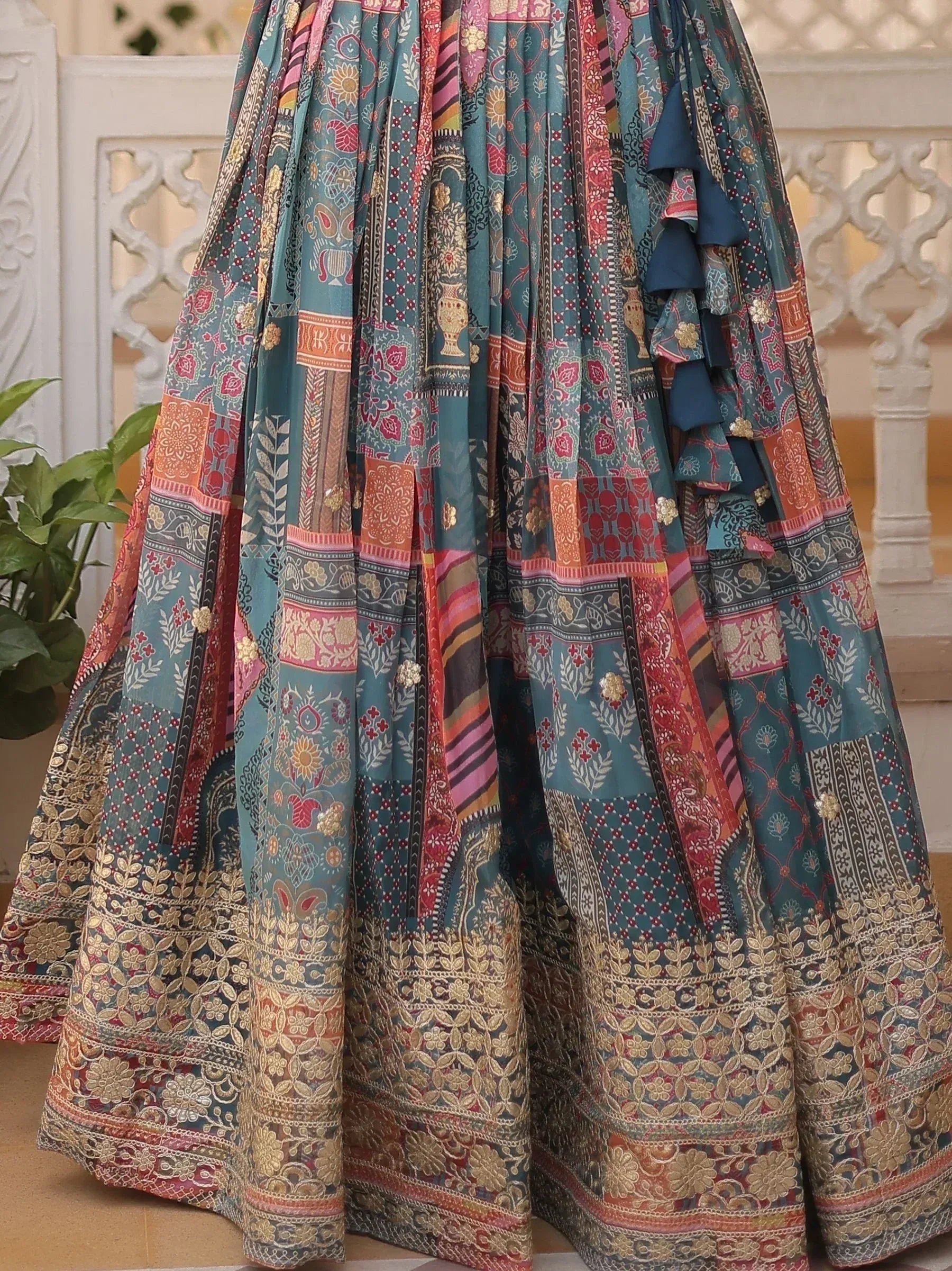 Teal patchwork lehenga with floral and geometric prints, gold embroidery, and ruffle detailing for Indian ethnic wear