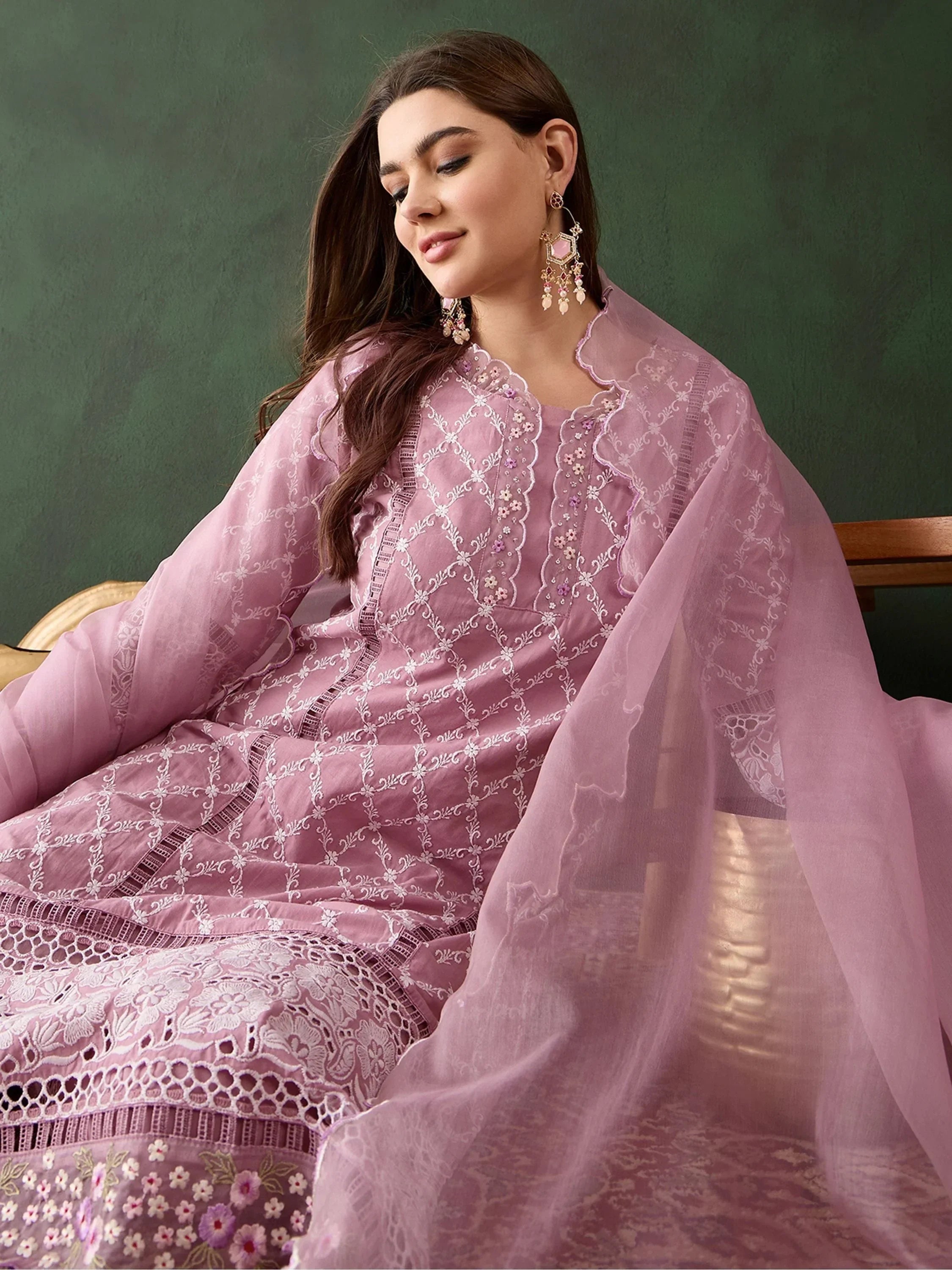 Woman in pastel pink embroidered Indian ethnic suit with matching dupatta and statement earrings