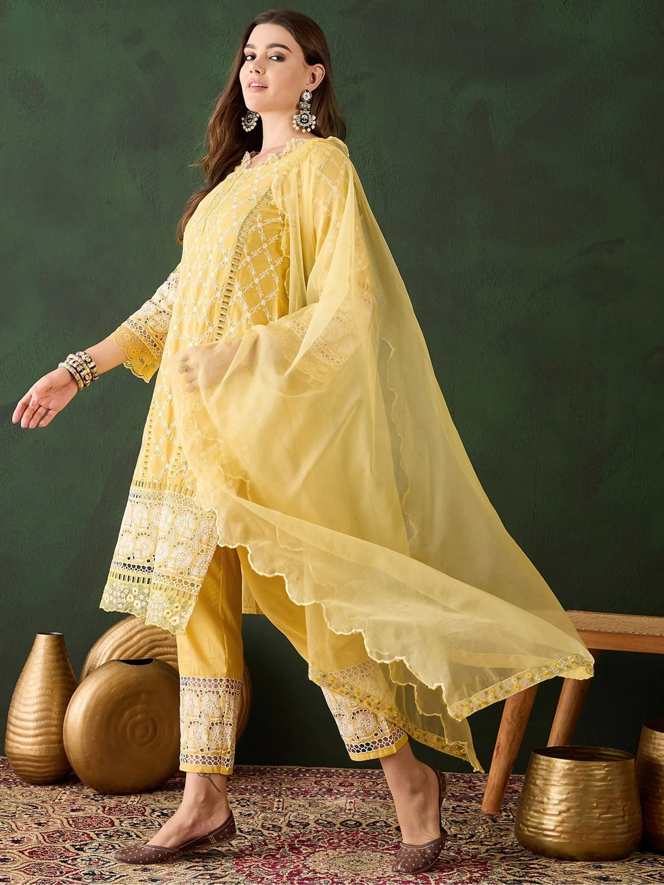 Woman in yellow embroidered salwar kameez with matching dupatta, traditional jewelry, and juttis
