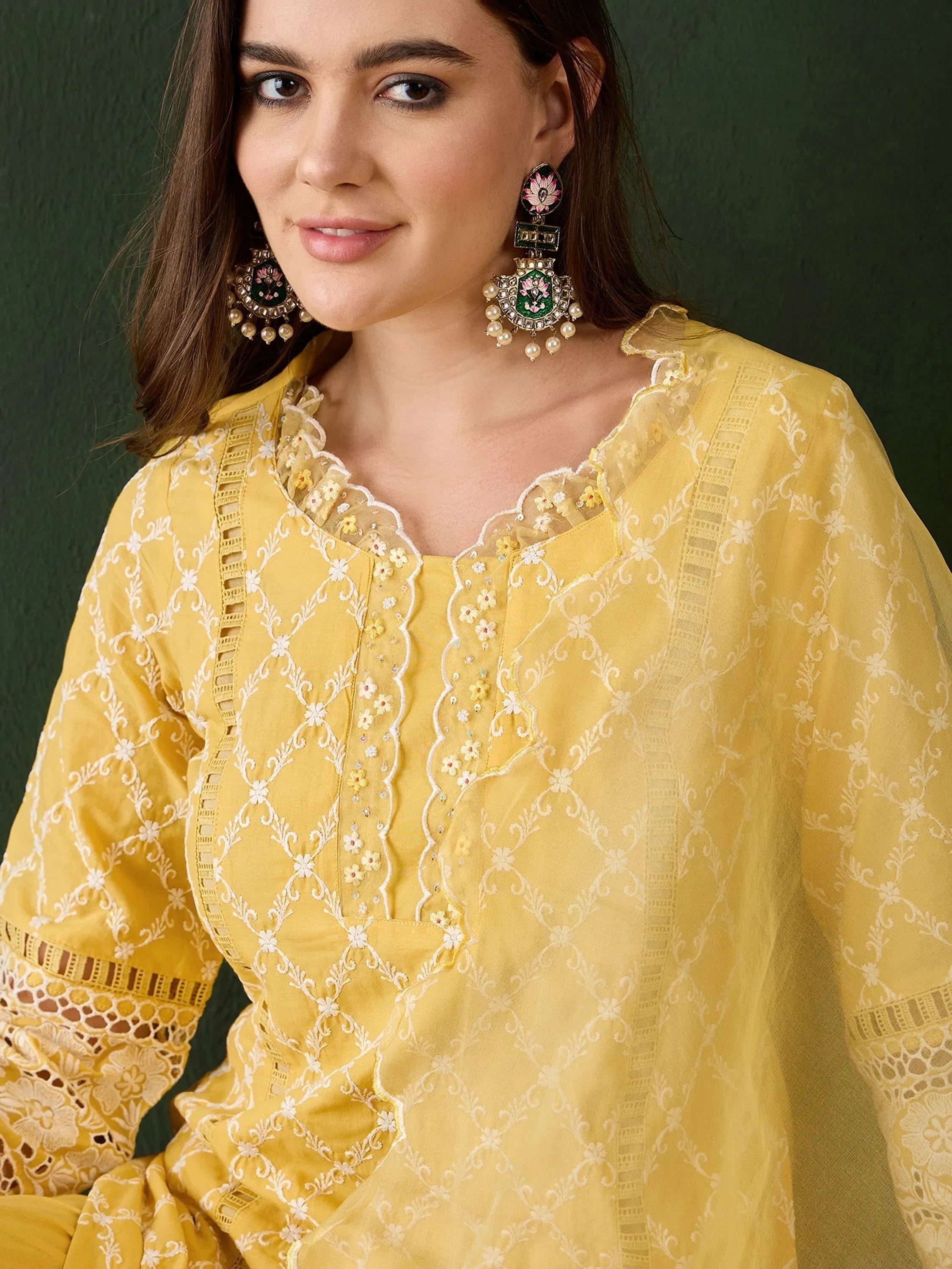 Woman in a yellow embroidered kurta with lace details and statement ethnic earrings