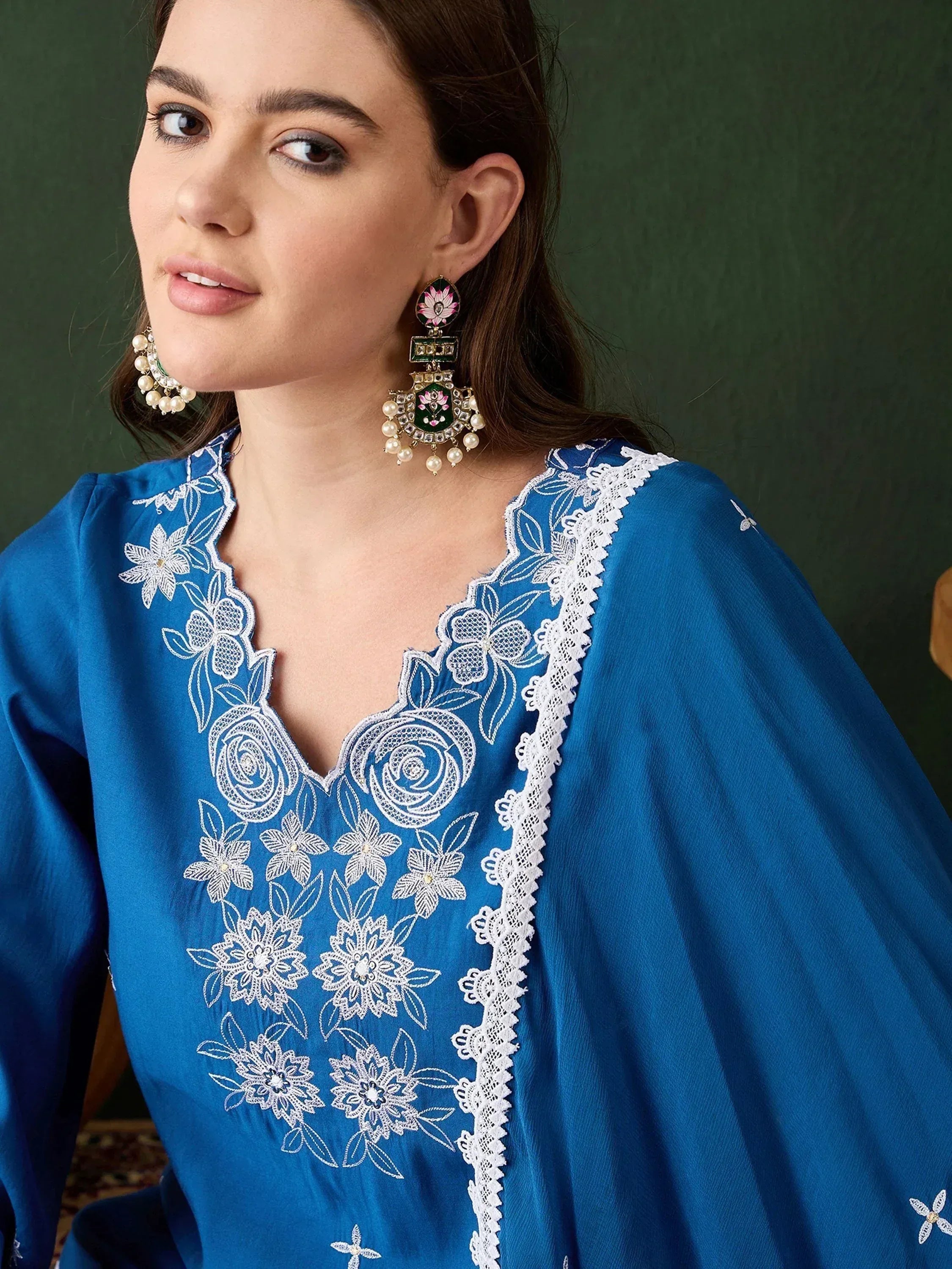 Blue ethnic kurti with white floral embroidery and lace detailing, paired with ornate earrings