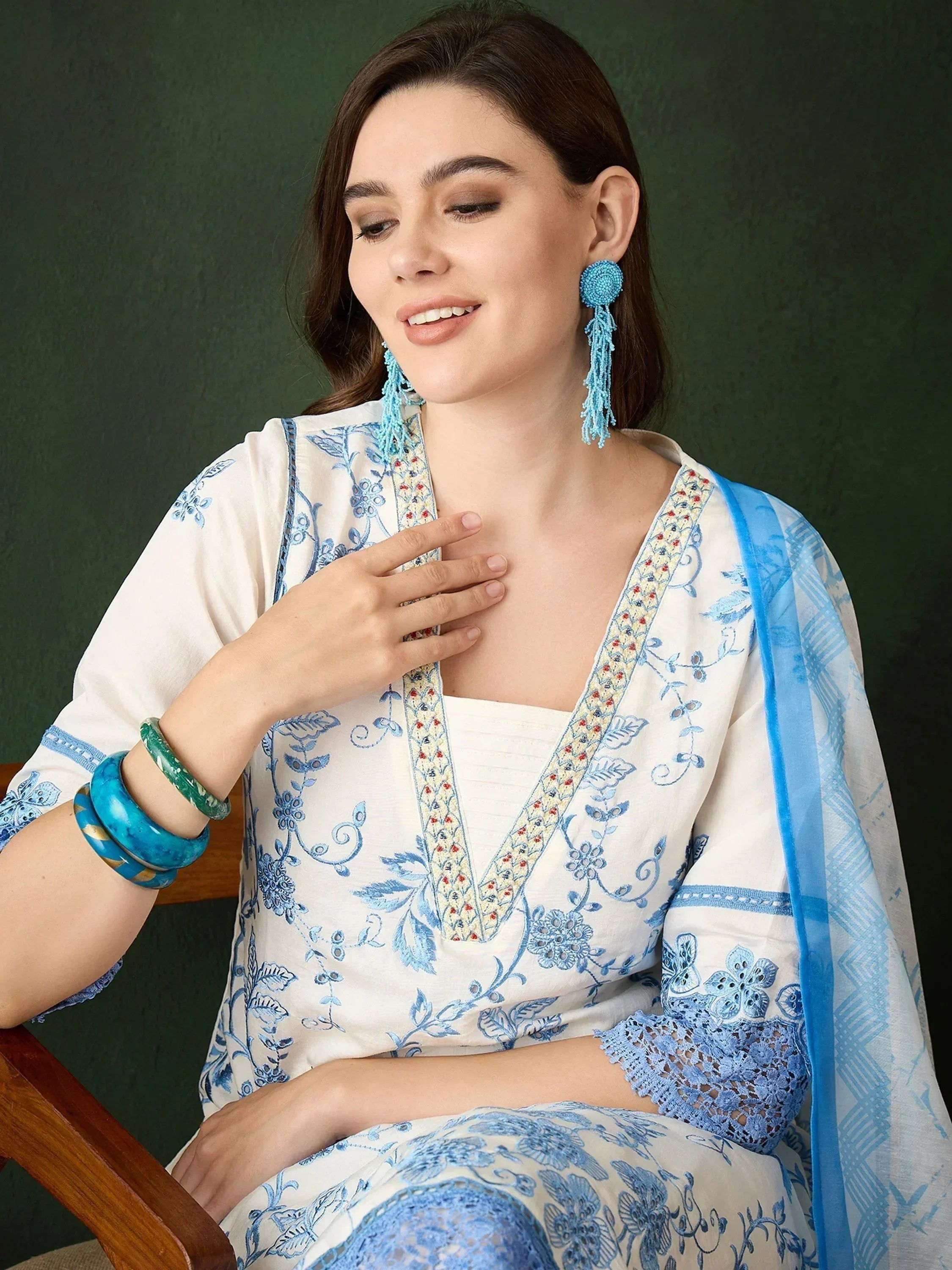 Woman in white and blue embroidered salwar kameez with matching dupatta and tassel earrings