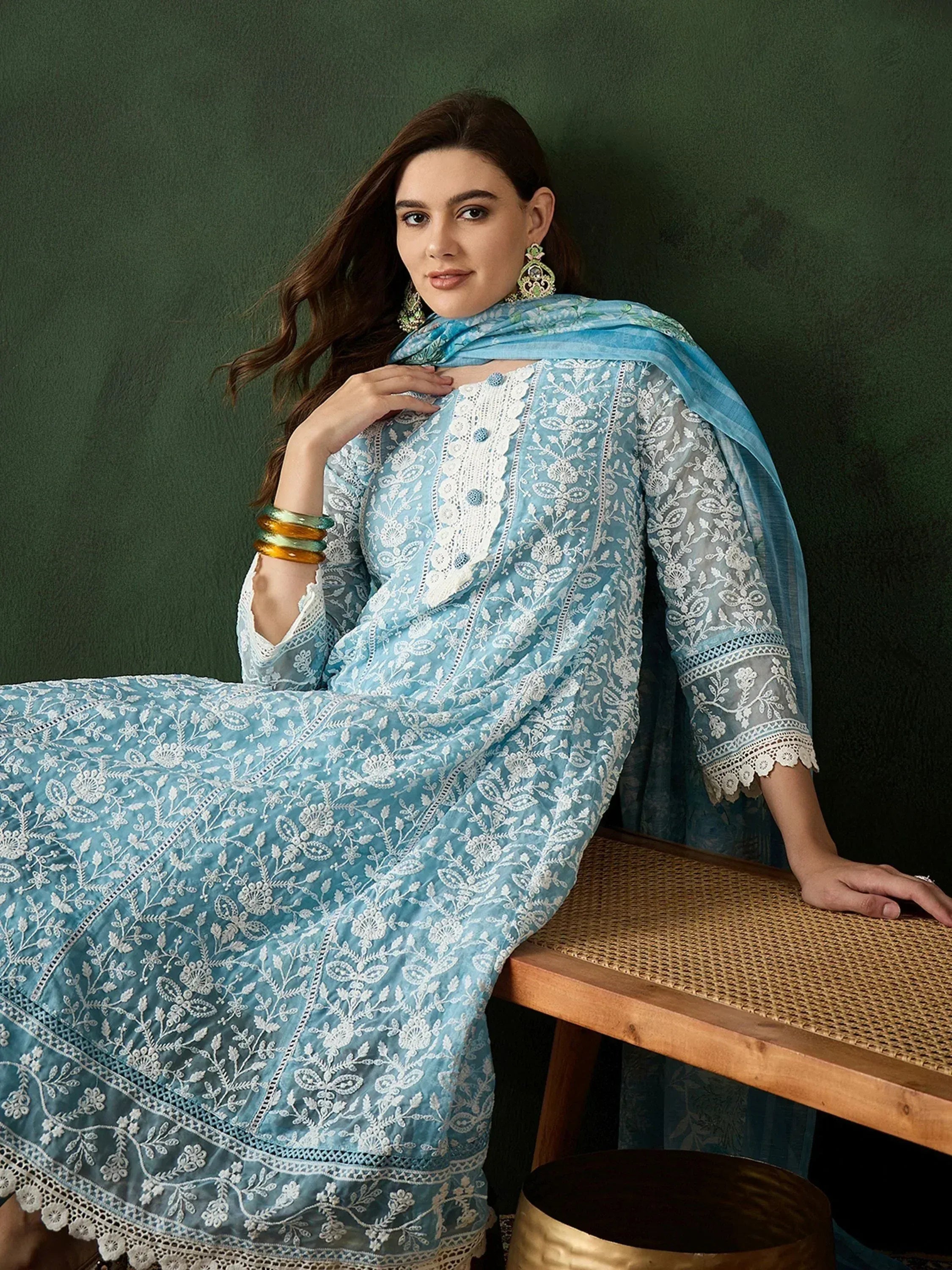 Light blue embroidered salwar kameez with white floral detailing and matching dupatta, styled with statement earrings.