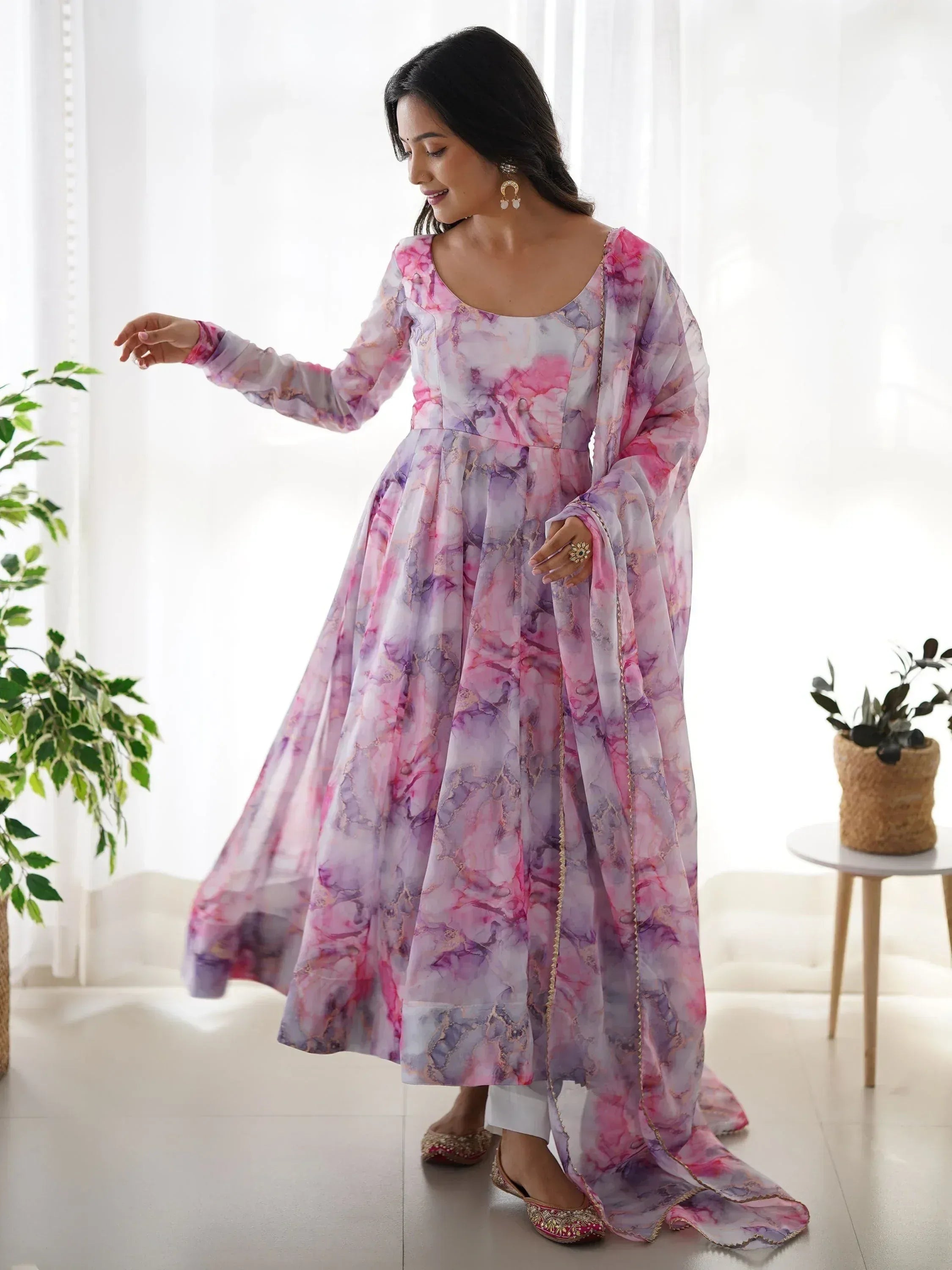 Pink and purple floral print ethnic gown with gold trim, styled with white pants and juttis for festive occasions