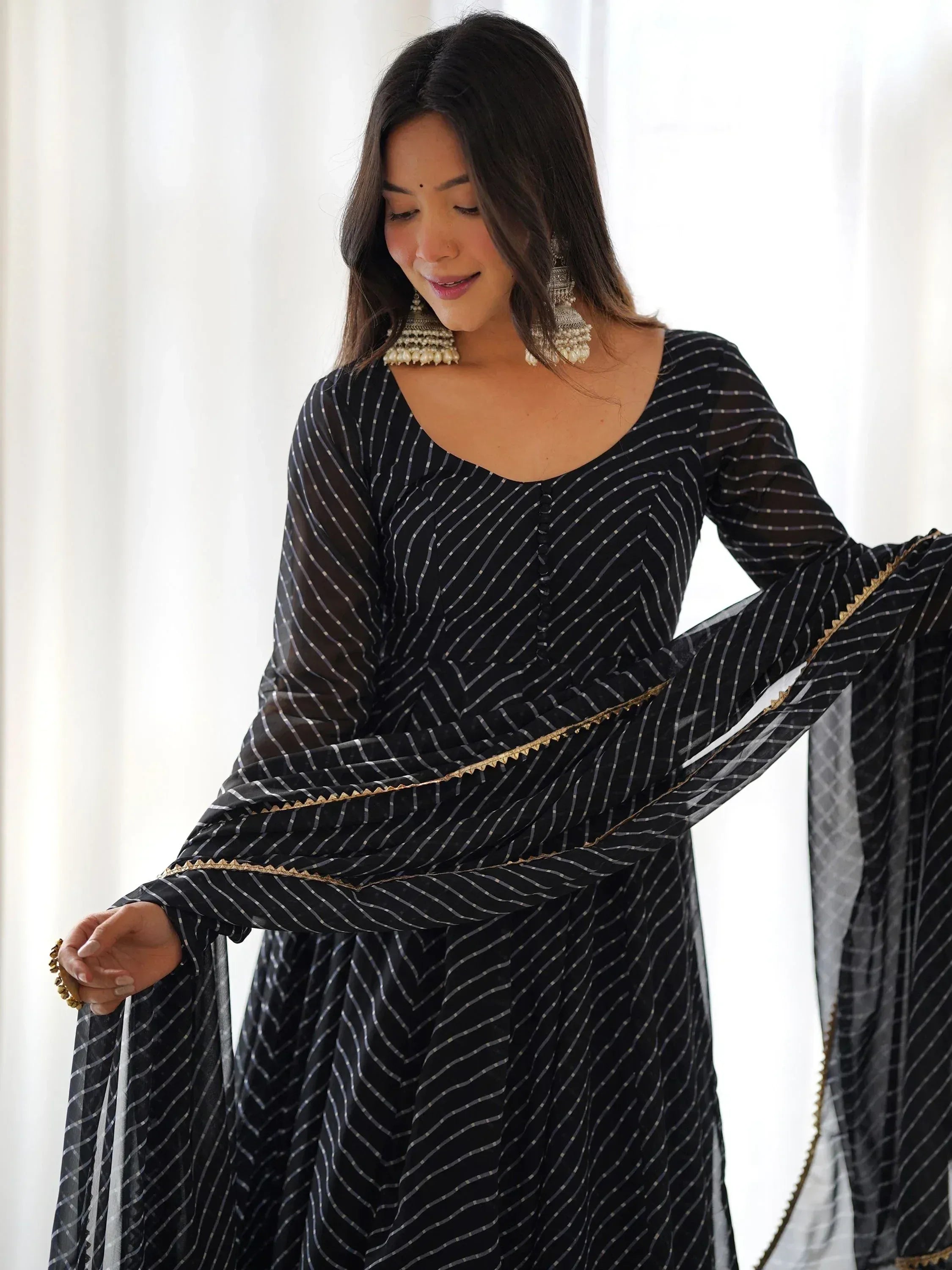 Black striped ethnic gown with gold trim, styled with statement earrings for Indian wear