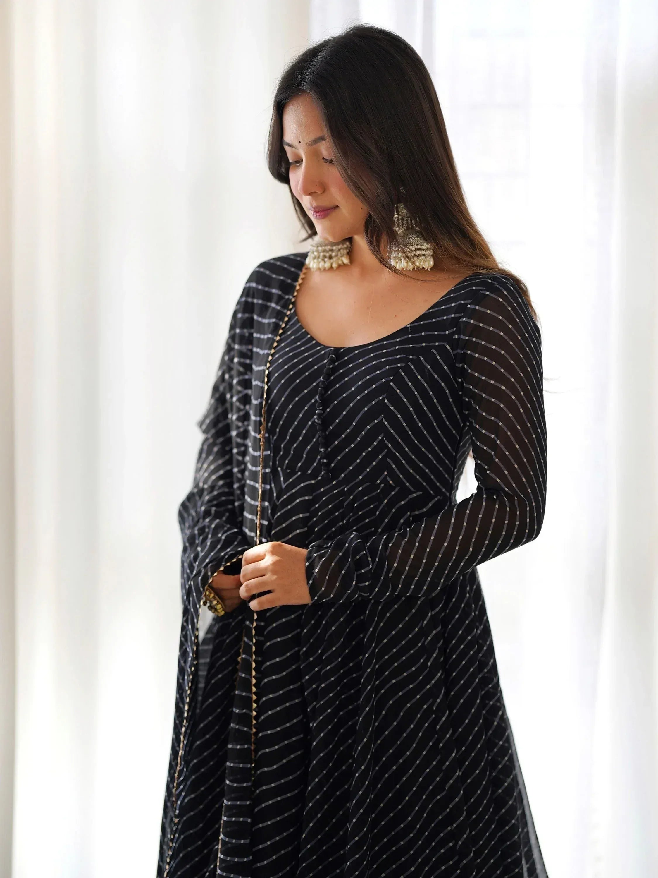 Black striped ethnic gown with sheer sleeves and gold trim, paired with statement jewelry