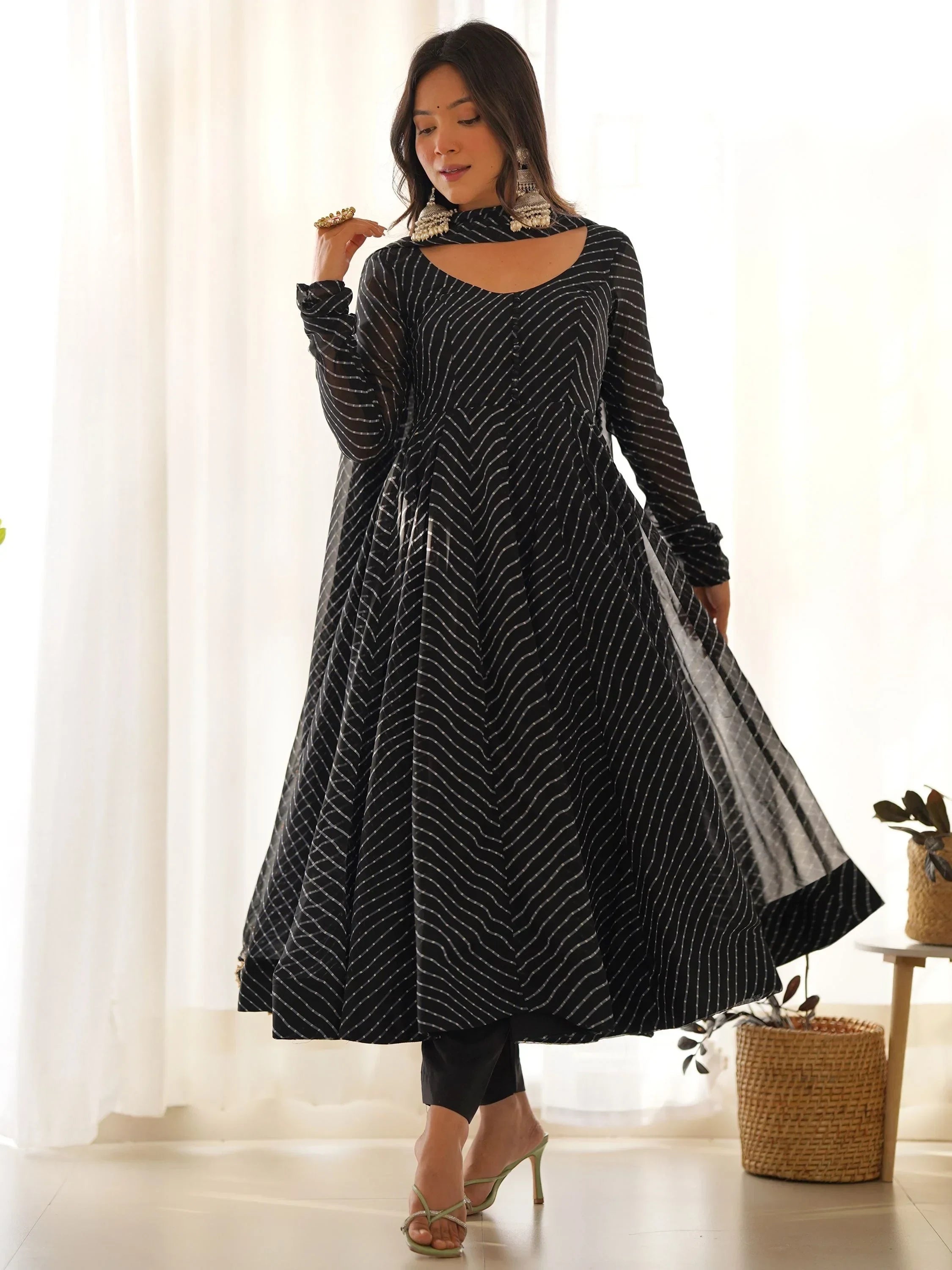 Woman wearing black ethnic Anarkali suit with white striped pattern, dupatta, and statement jewelry