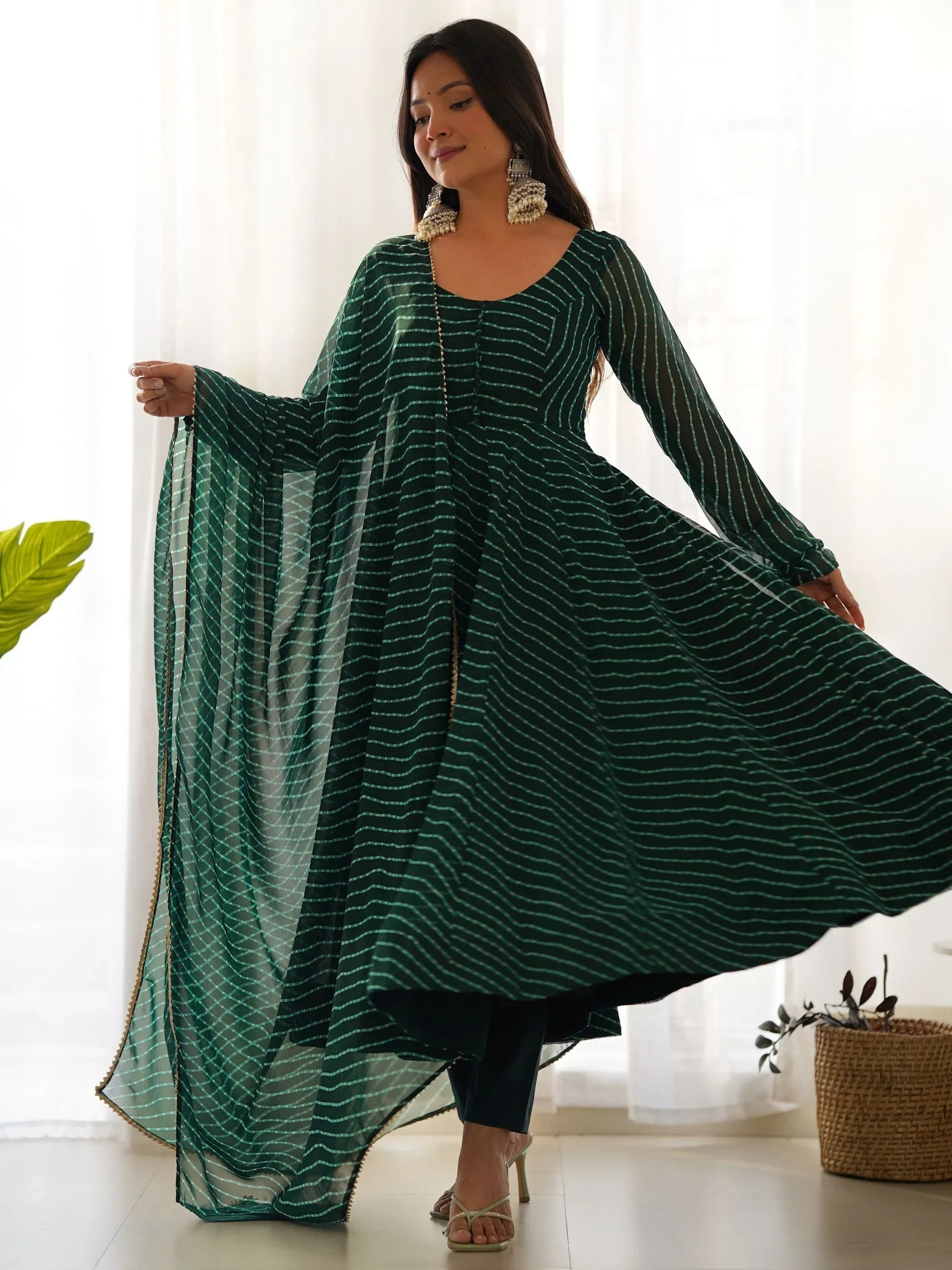 Woman wearing green striped ethnic Anarkali gown with dupatta and statement earrings