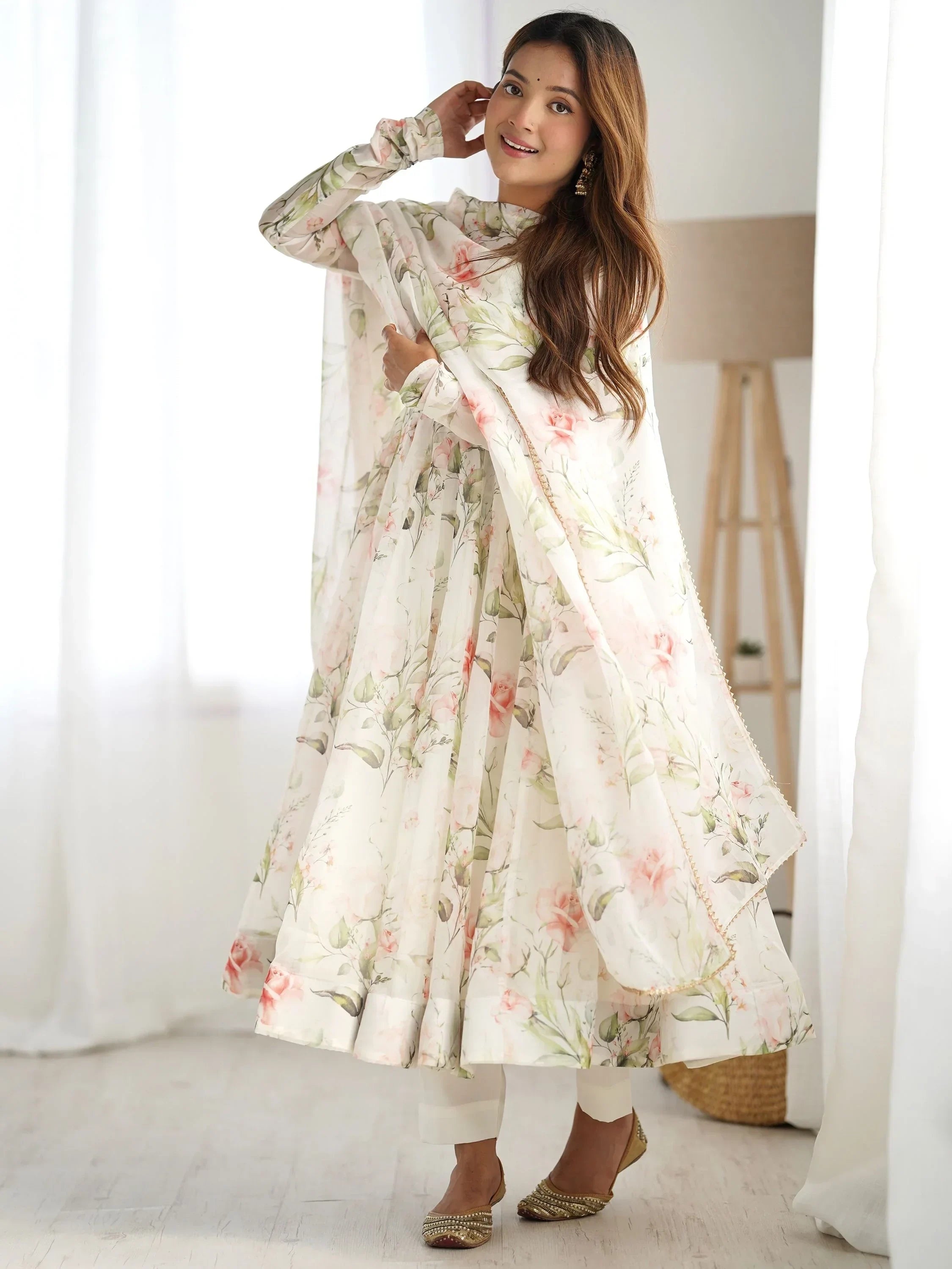 Woman in a floral printed Anarkali suit with dupatta, posing in a bright indoor setting
