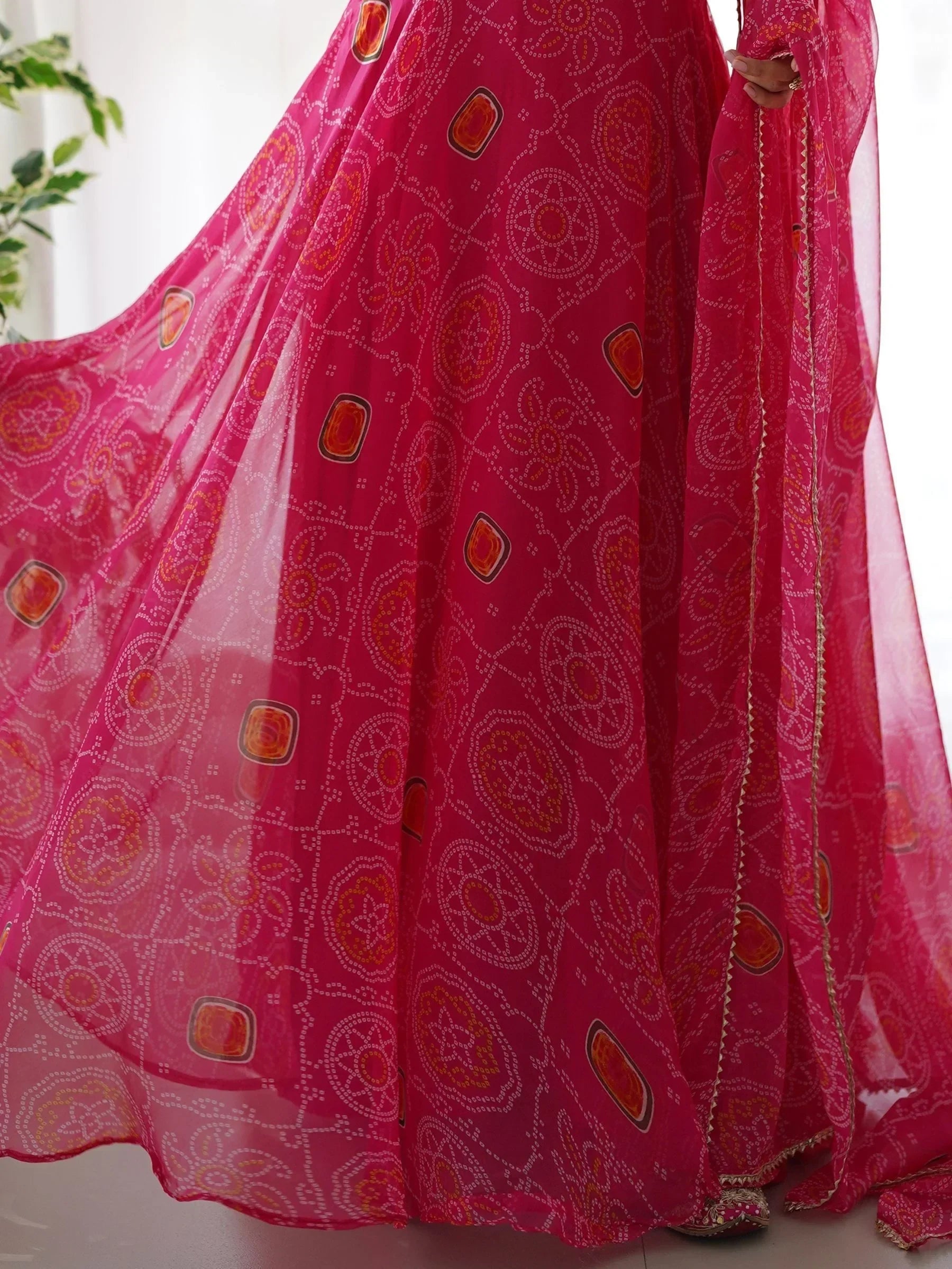 Bright pink Bandhani saree with traditional white and yellow patterns, sheer fabric