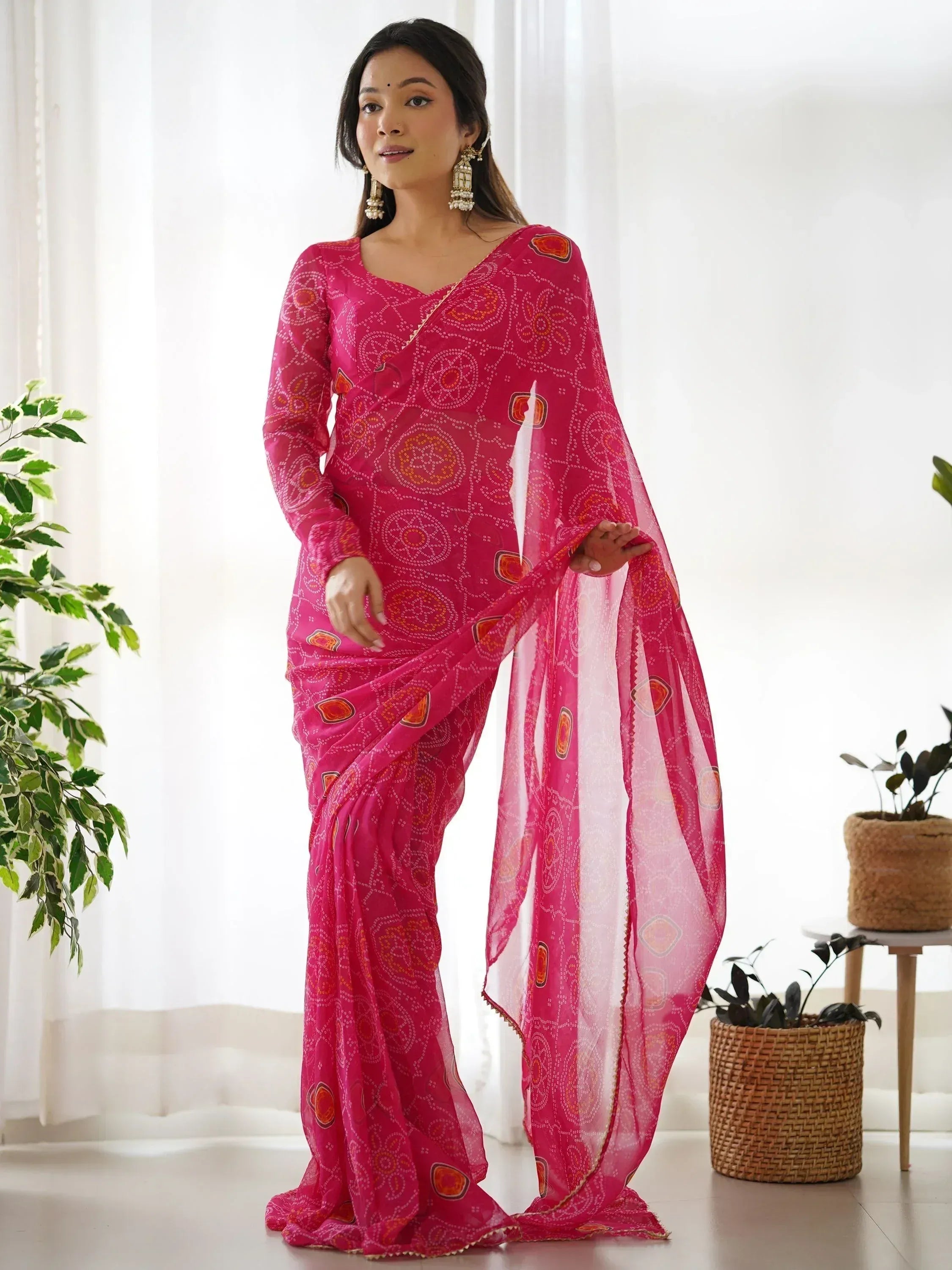 Pink printed saree with ethnic motifs, styled with gold earrings for traditional Indian wear