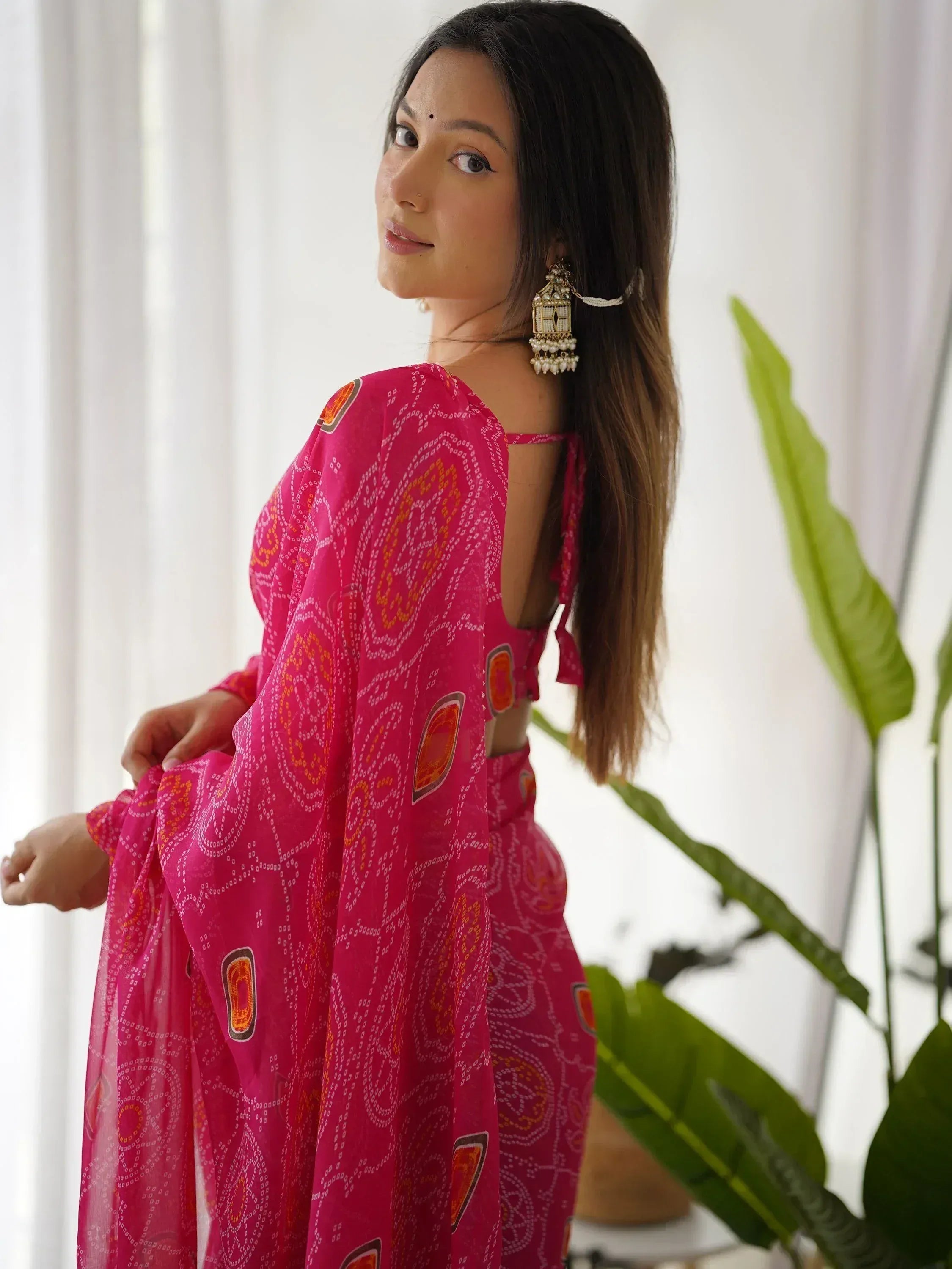 Woman in vibrant pink printed ethnic salwar kameez with back cutout, styled with jhumka earrings