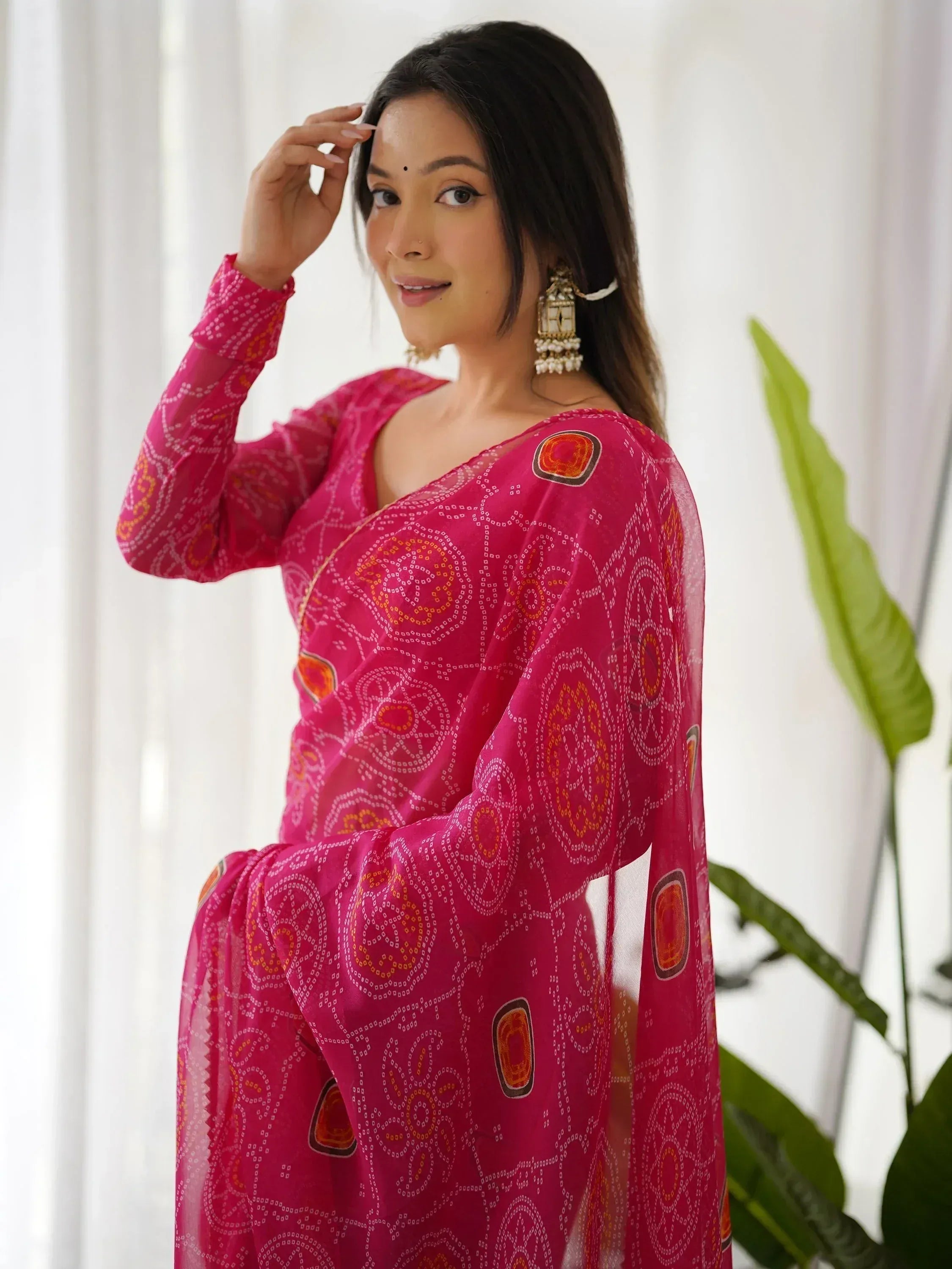 Woman in vibrant pink ethnic salwar kameez with geometric print, styled with jhumka earrings for festive occasions