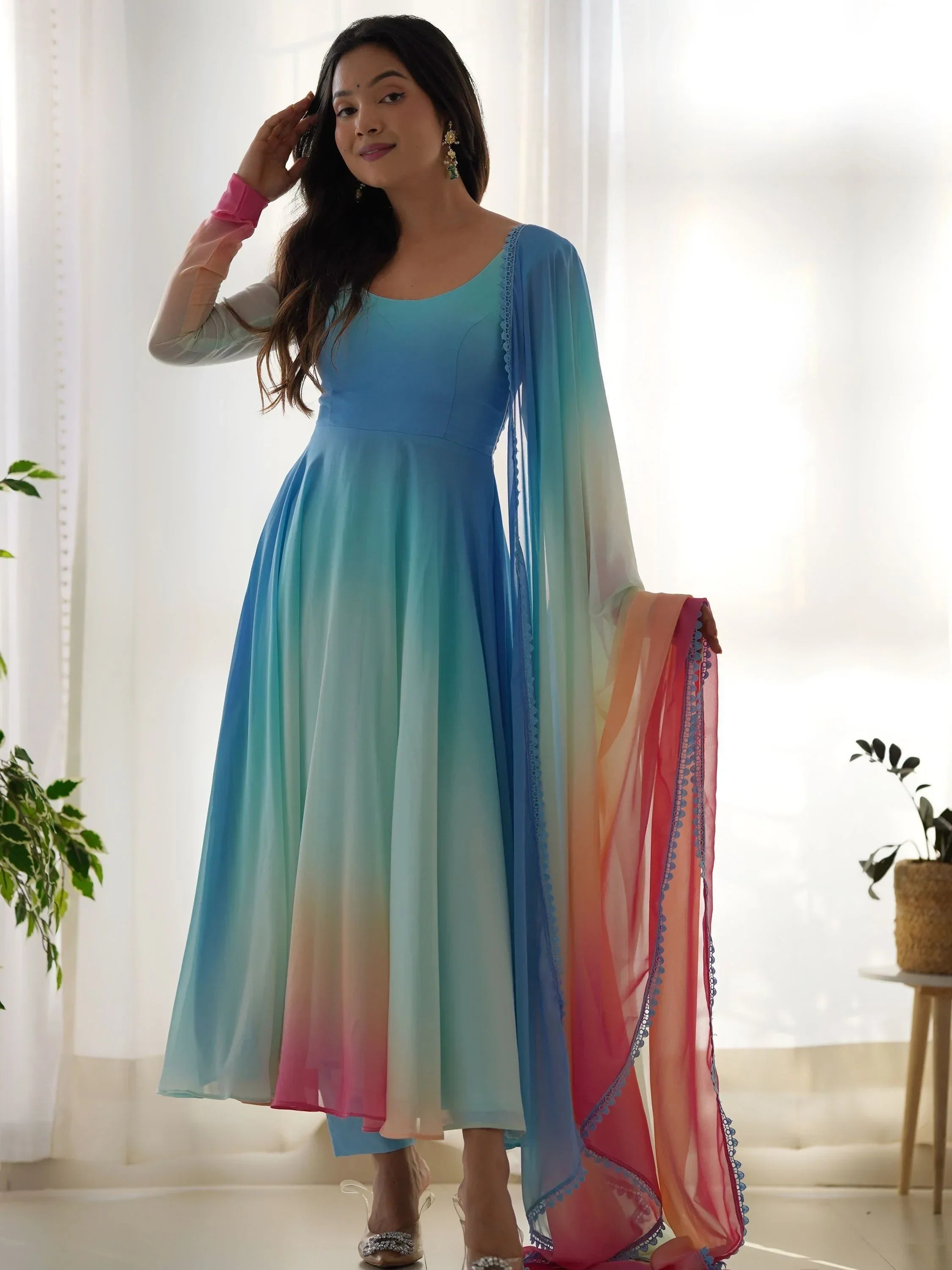 Woman wearing pastel ombre ethnic gown with dupatta and chandelier earrings indoors