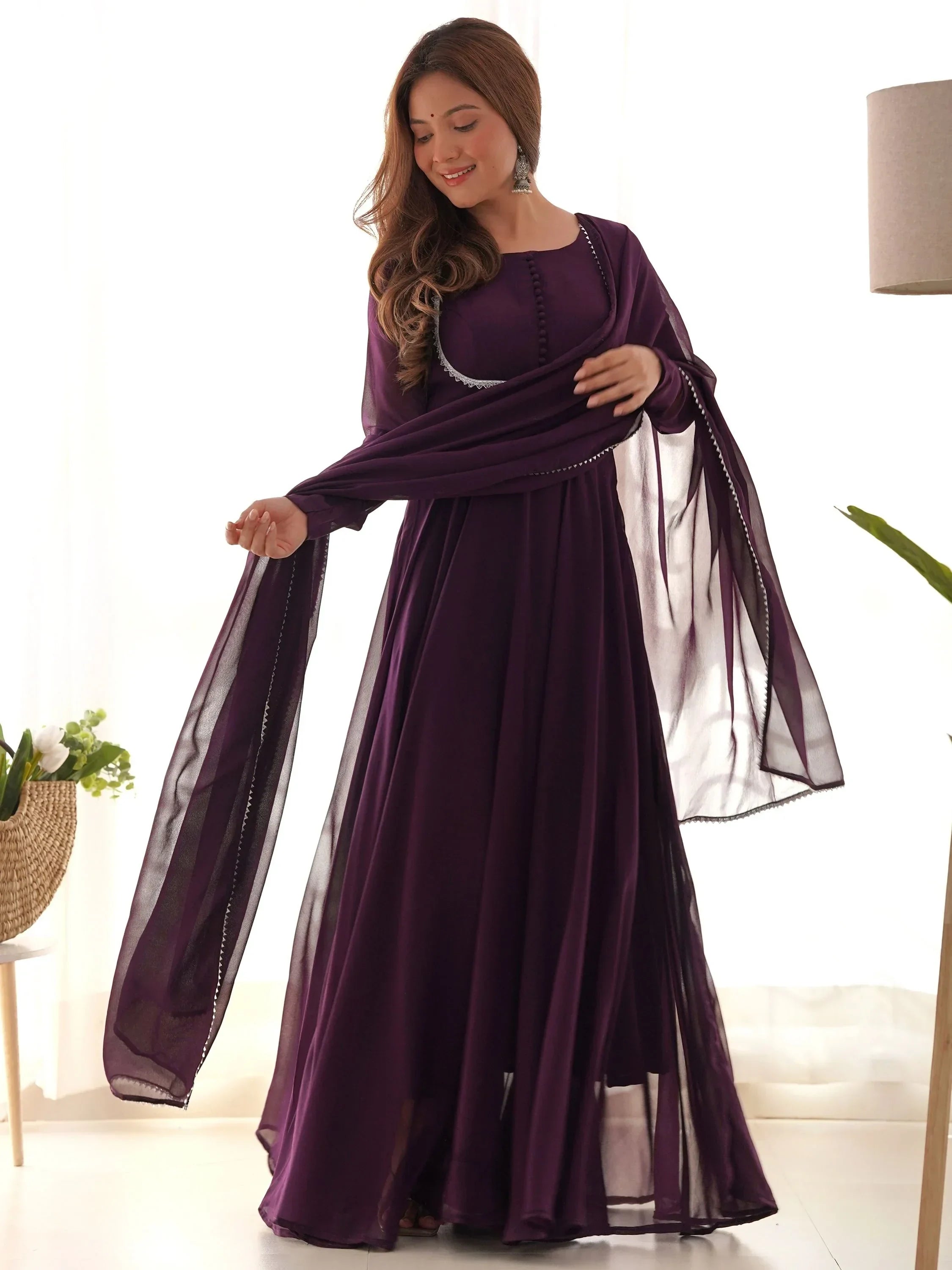 Woman wearing purple ethnic gown with dupatta, featuring flowing fabric and traditional design