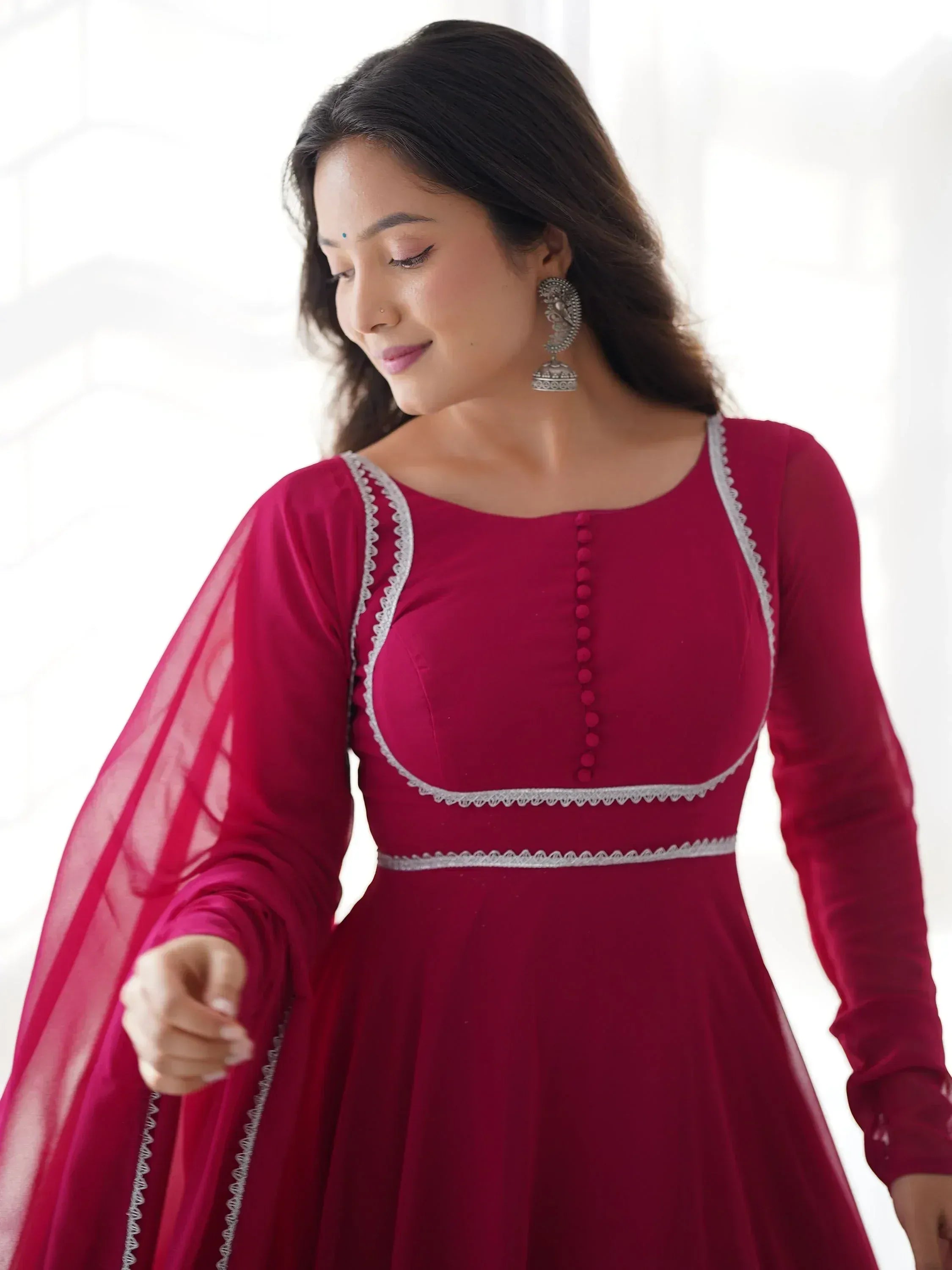 Woman in maroon ethnic gown with silver lace detailing and sheer sleeves, perfect for Indian occasions
