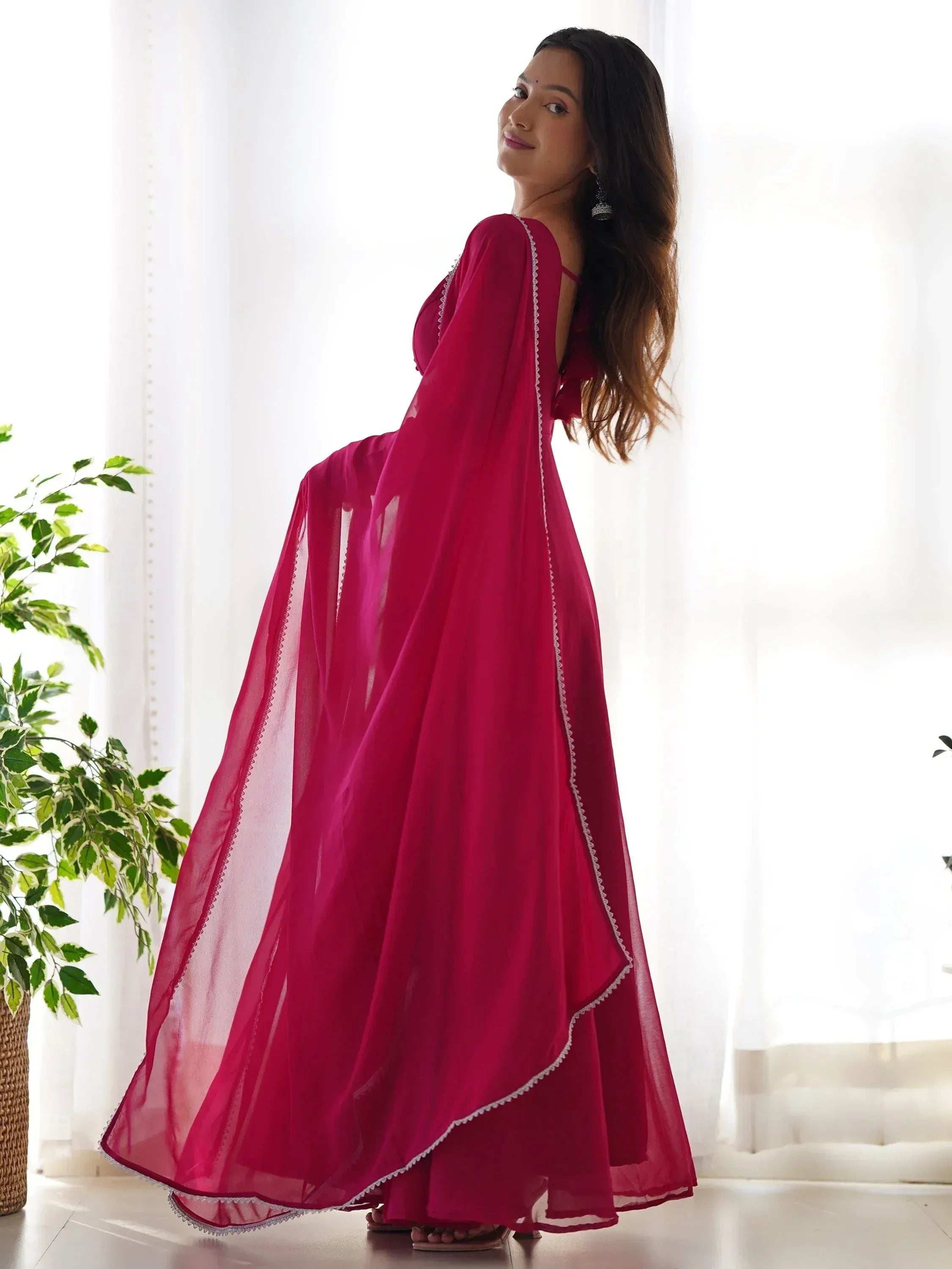 Woman in elegant magenta ethnic gown with sheer cape, perfect for Indian occasions and festive wear.