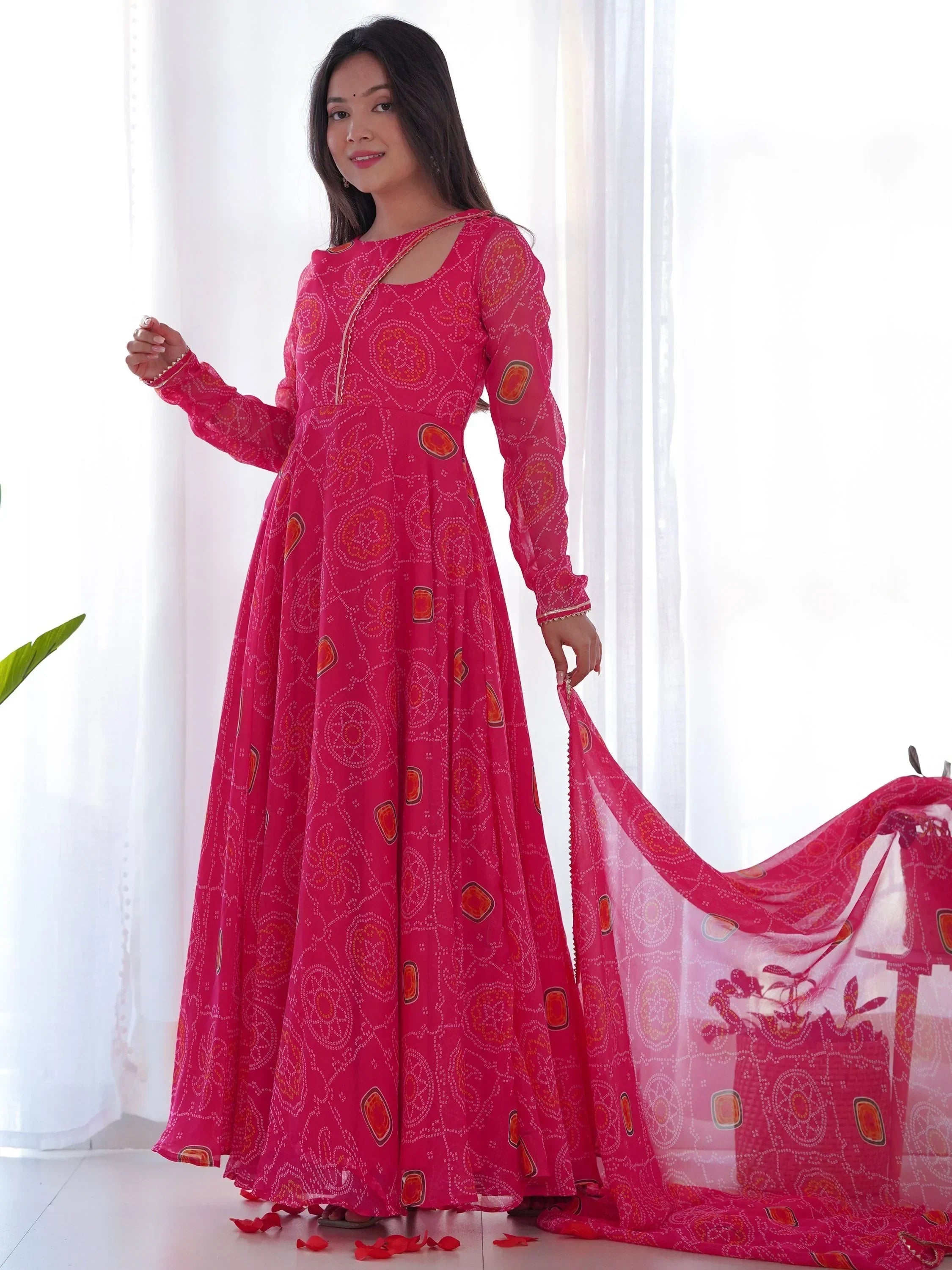 Woman wearing bright pink ethnic gown with traditional bandhani print and dupatta