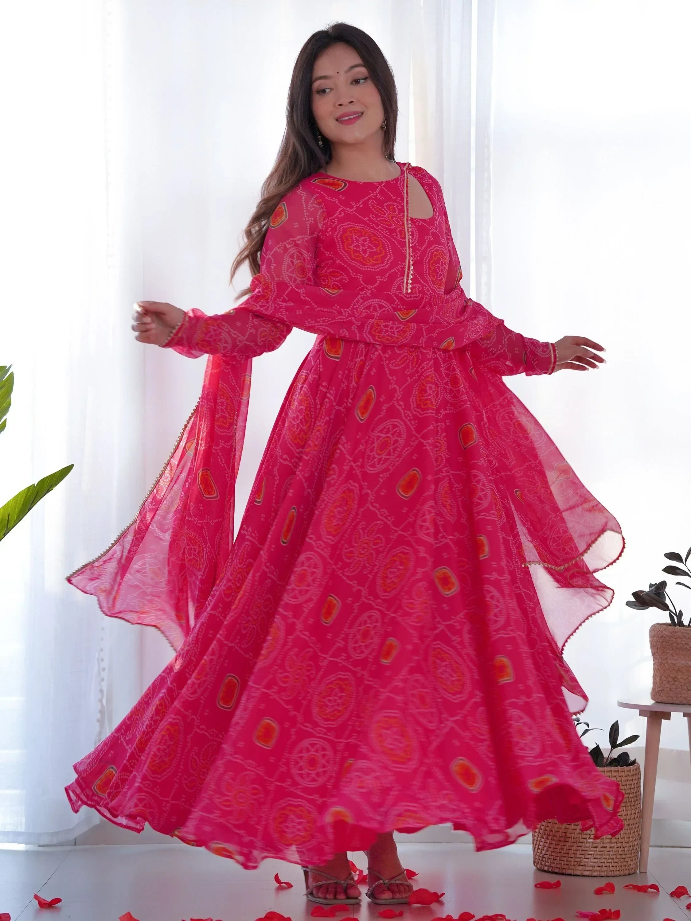 Woman twirling in bright pink ethnic gown with traditional patterns in a modern indoor setting