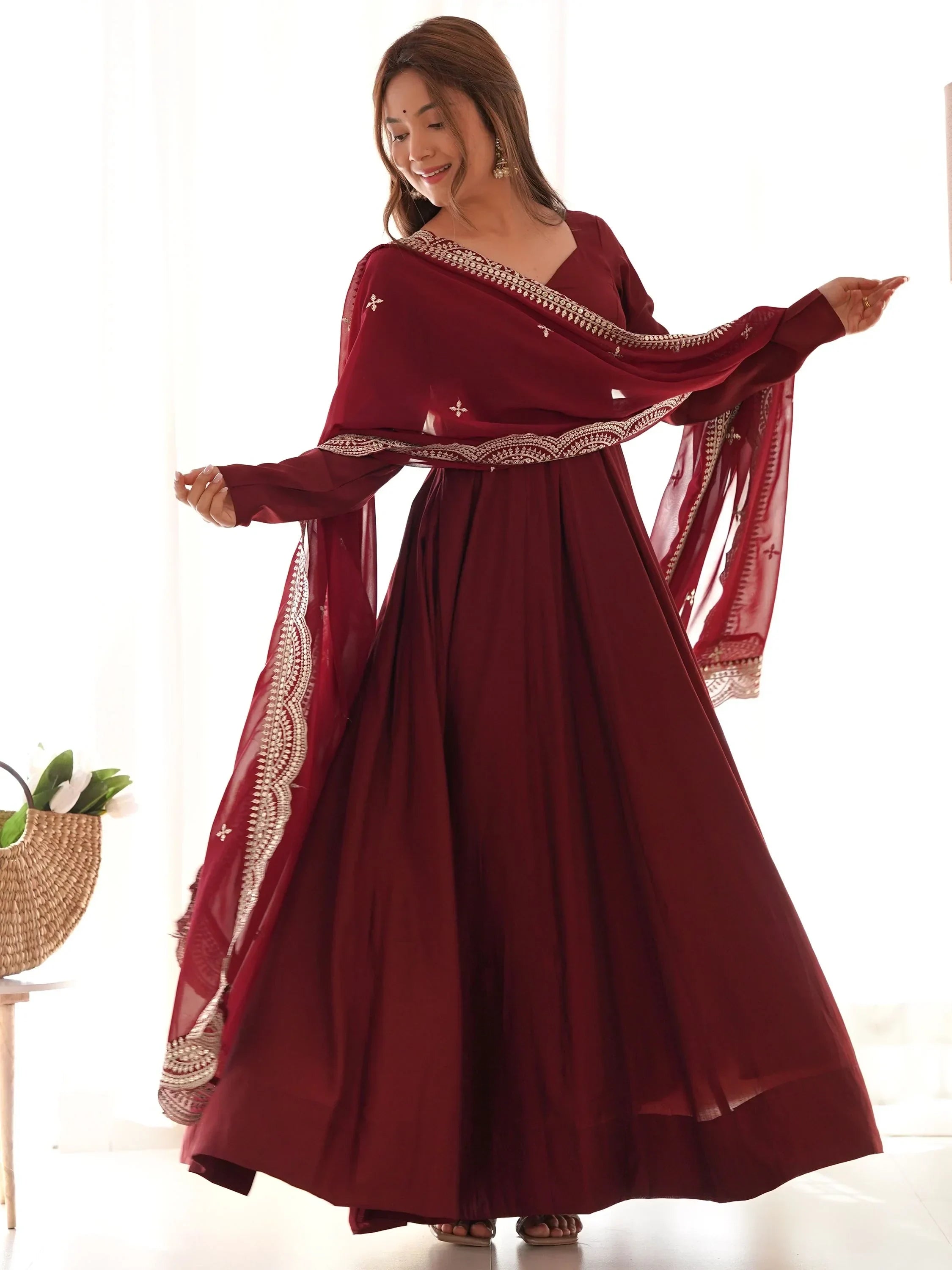 Woman wearing maroon ethnic gown with embroidered dupatta, traditional Indian attire